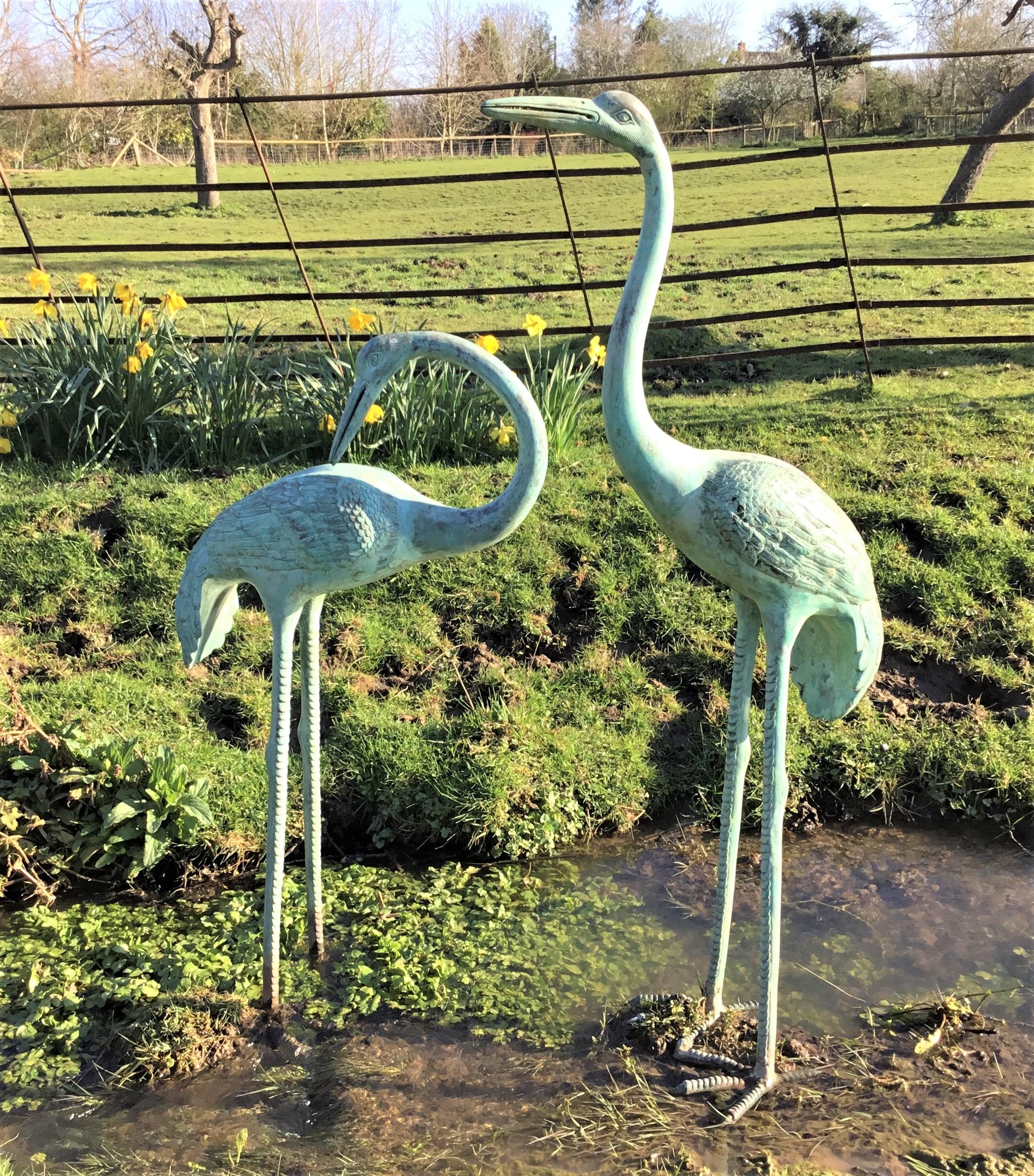 An impressive early 20th century large pair of Japanese bronze cranes, life-size with a verdigris patination, realistically sculptured with detailed feathers, scaled legs and webbed feet. The large male bird standing alert with his neck and head
