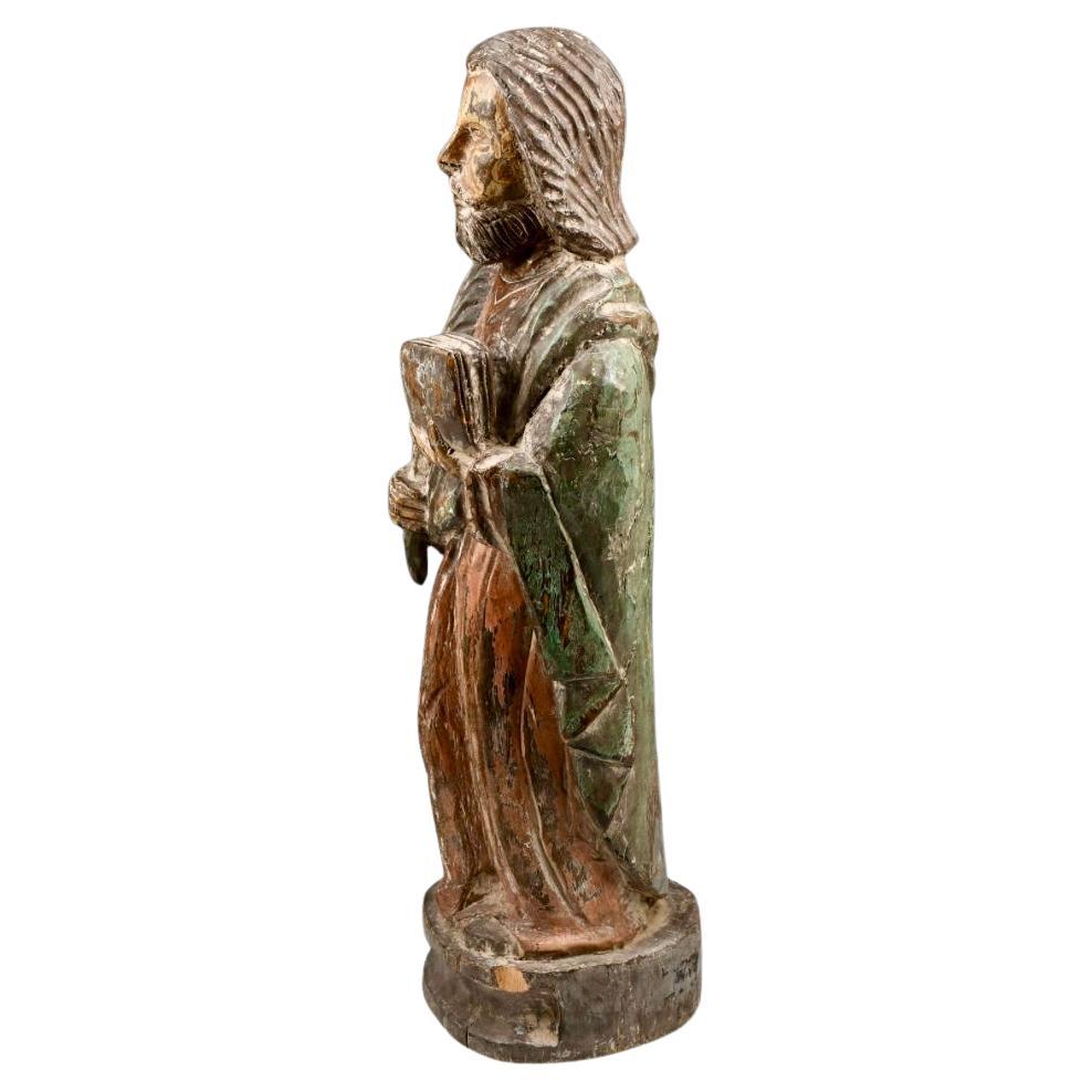 Figura religiosa splendidamente intagliata, in legno massiccio e dipinta nei colori del rosso, del marrone e del verde. La figura è barbuta e tiene un libro nella mano sinistra e una grande piuma nella mano destra, appoggiata su una base di legno.