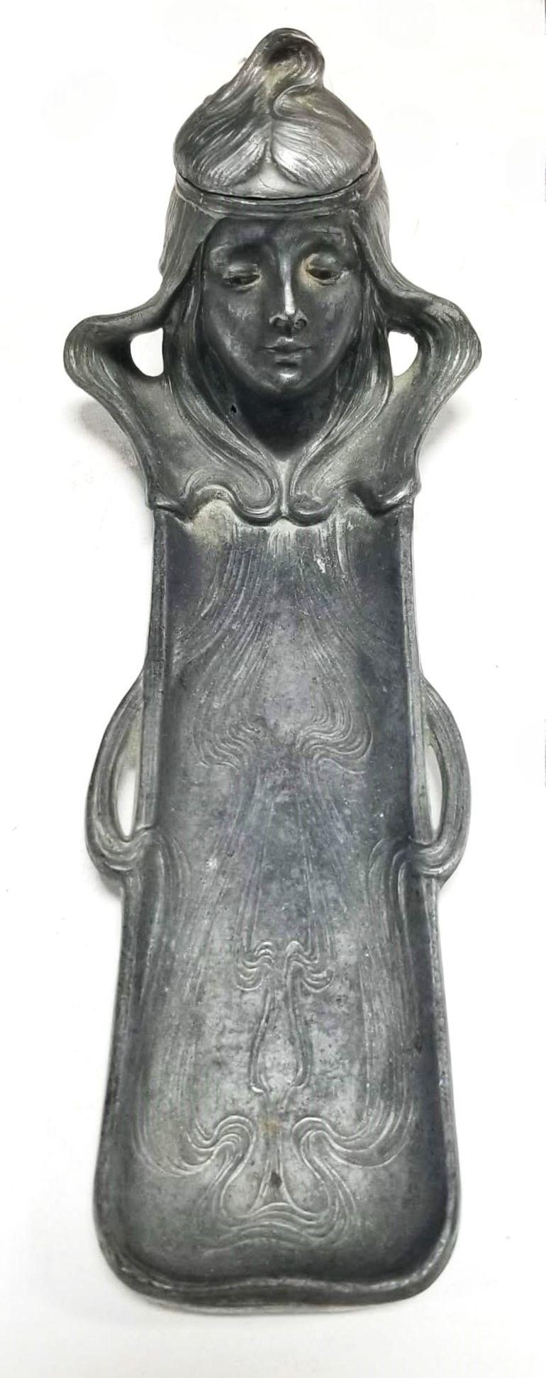 This exquisite vintage Art Nouveau inkwell and pen holder is a true testament to the elegance and intricate craftsmanship of the early 20th century. Crafted from ornate metalwork, this inkwell takes on the form of a beautifully detailed woman's head