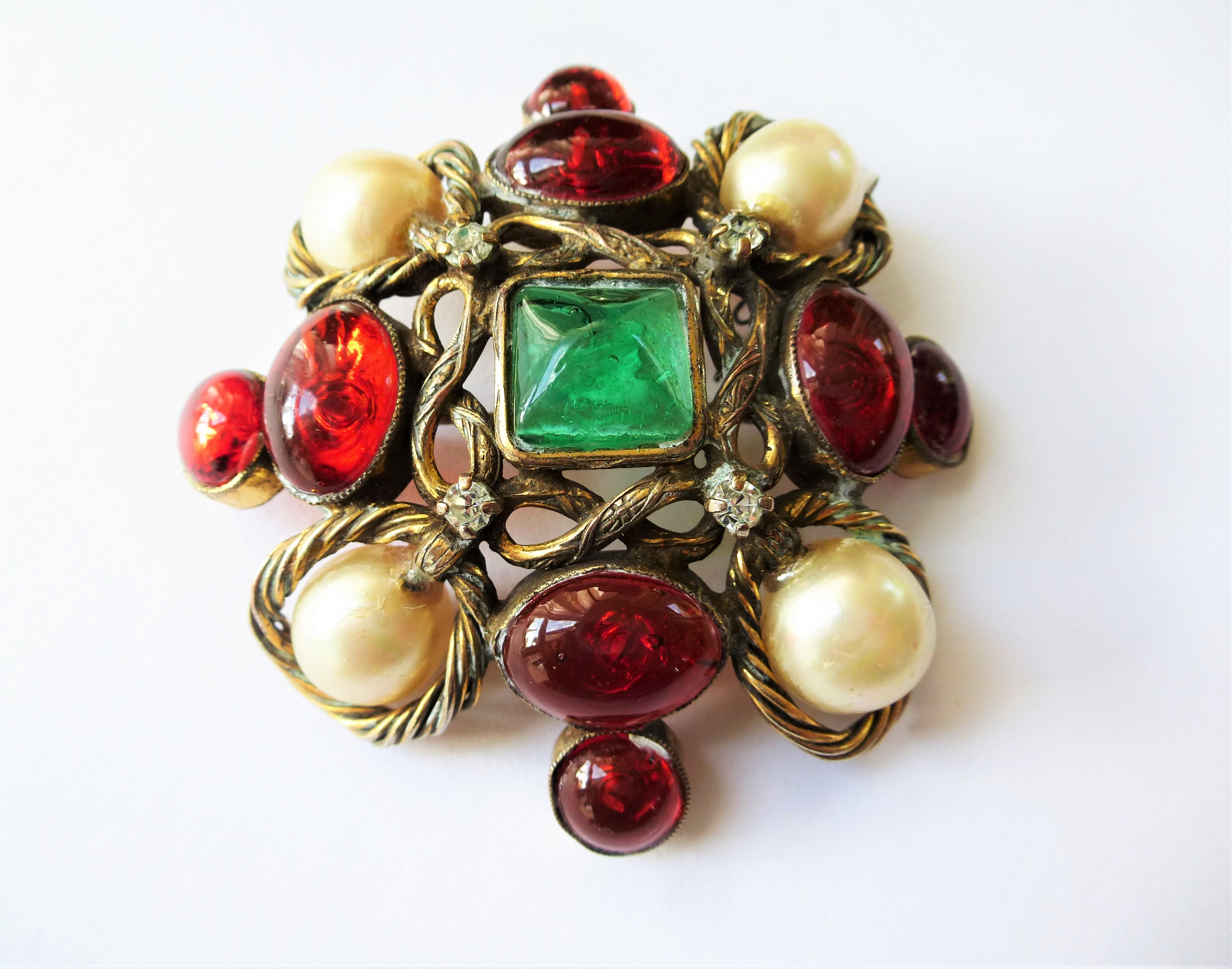 A beautiful early unsigned Chanel brooch from the 1960s made by Robert Goossens Paris. 
The beautiful green and red glass stones from the House of Gripoix. 4 well-preserved fake pearls decorate this beautiful brooch,  also 4 small set rhinestones.