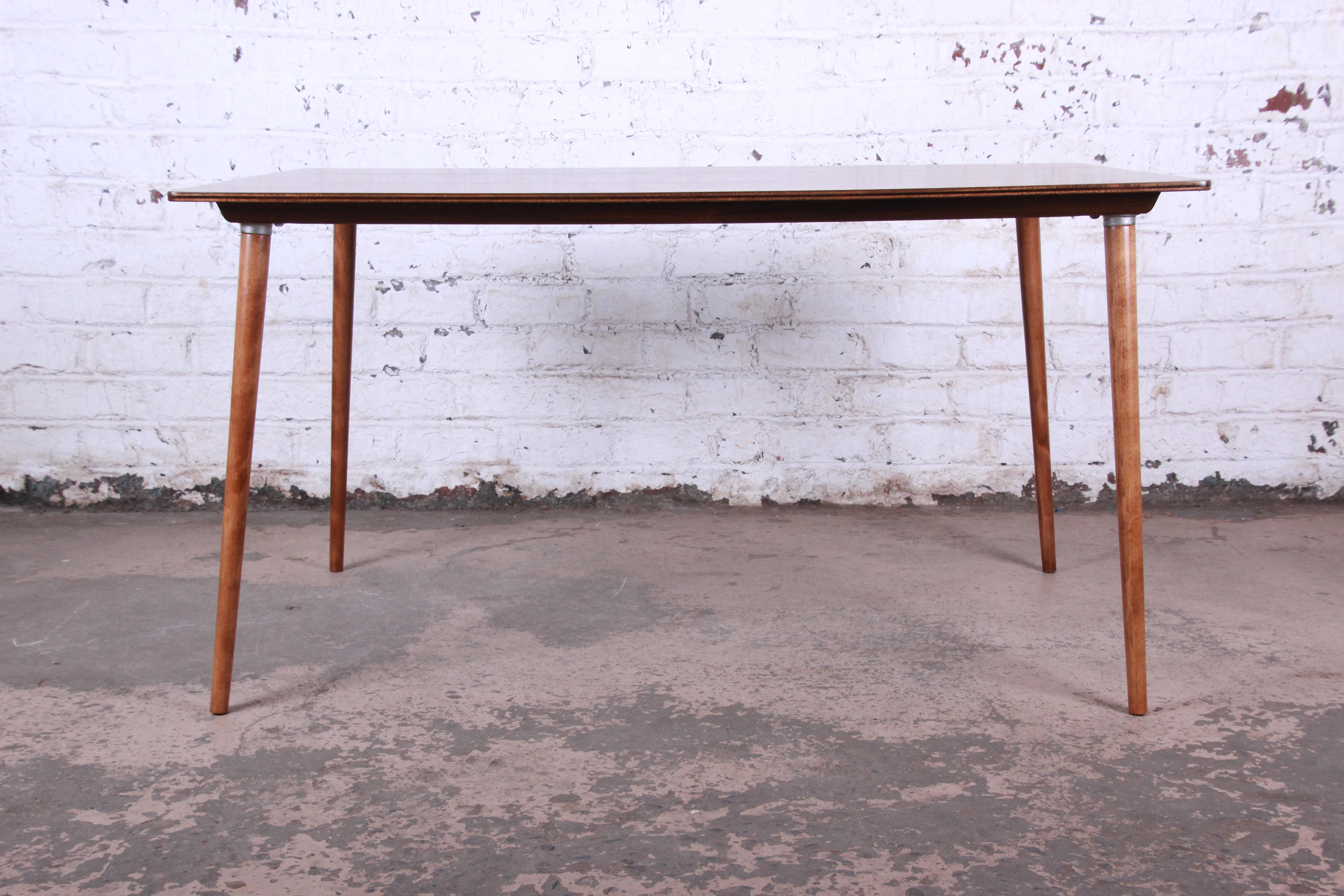 A rare and authentic DTW-3 dining table designed by Charles Eames for Herman Miller. The table has sleek Mid-Century Modern design and features a gorgeous walnut plywood top and solid maple legs, with aluminum hardware. The legs can be unscrewed for