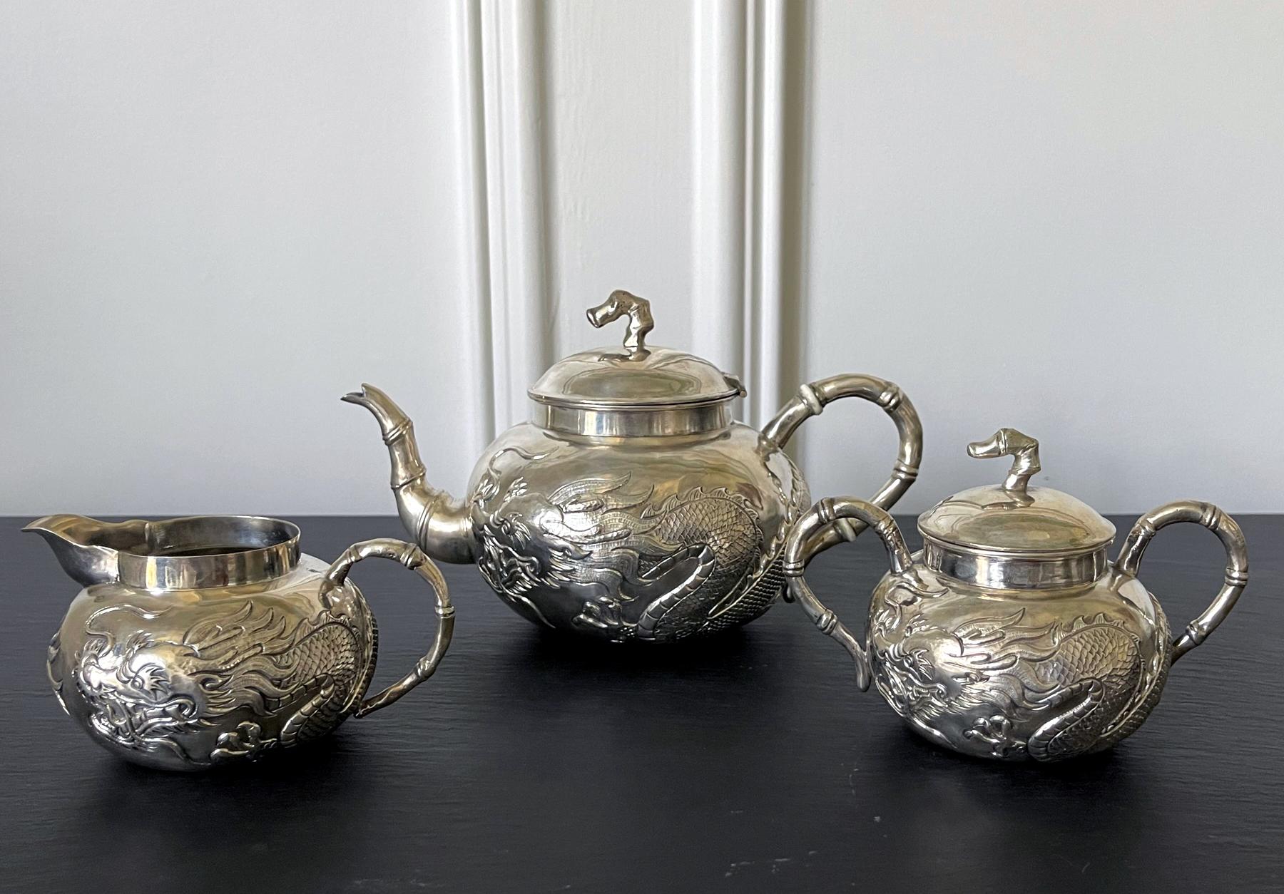 An early set of Chinese export sterling silver tea service circa 1840-70s. The service consists of a lidded tea pot, a creamer and a sugar bowl. The surface was beautifully decorated with chased high-relief dragons with tightly chased scales,