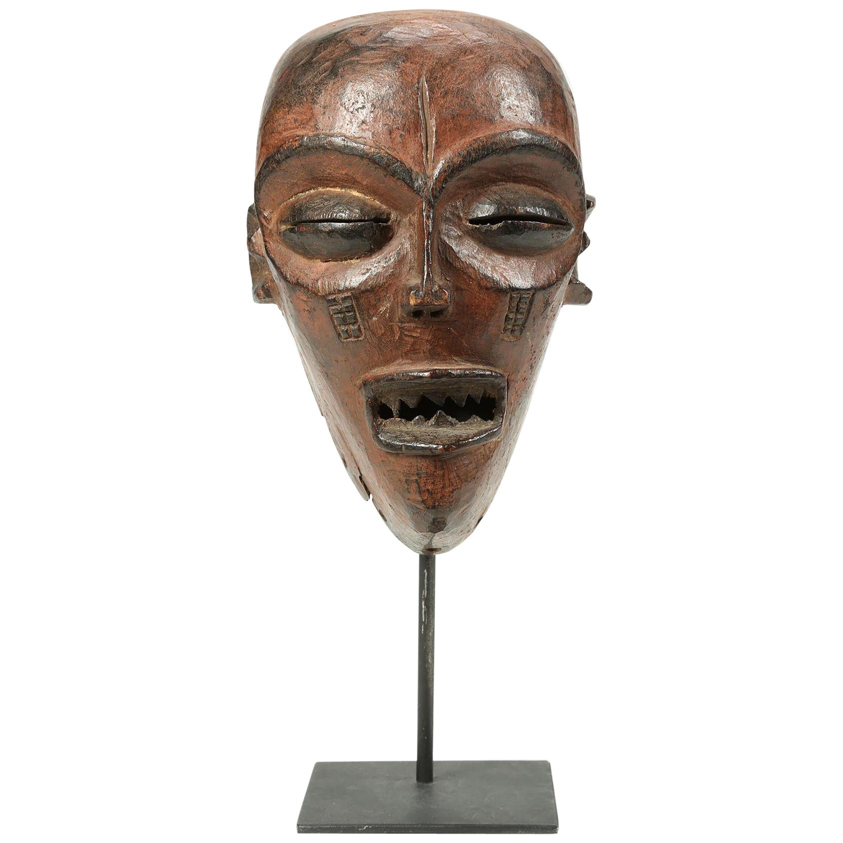 Early 20th century Chokwe wood mask with strong facial features on custom metal base, Angola or Congo, Africa. Traces of red pigment with black accents. Mask 8