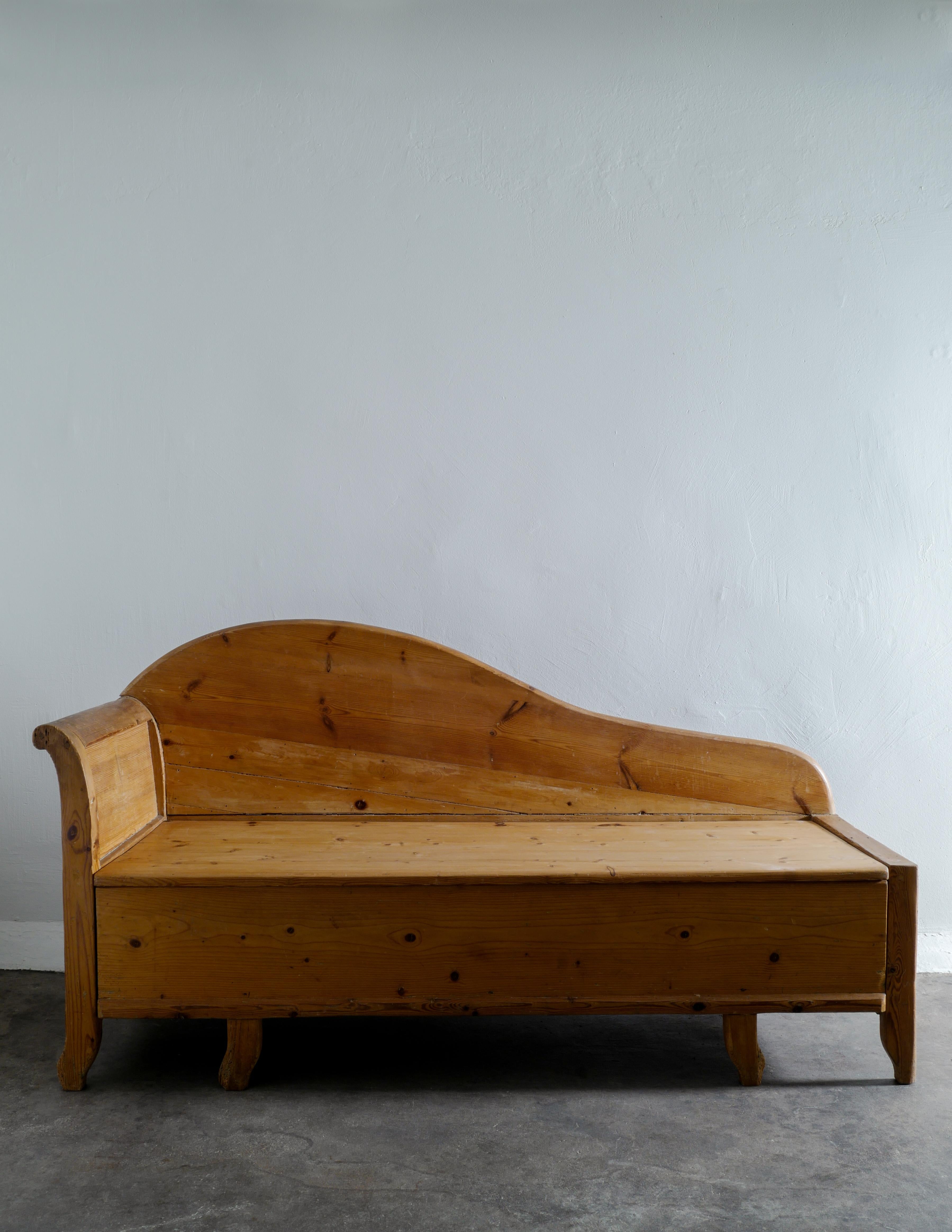 Rare and early midcentury sofa / bench in solid pine in style of Axel Einar Hjorth produced in Sweden early 1920s. In good vintage condition with patina from age and use. The back has a nice curved and sculptural freeform shape. Seat can be lifted