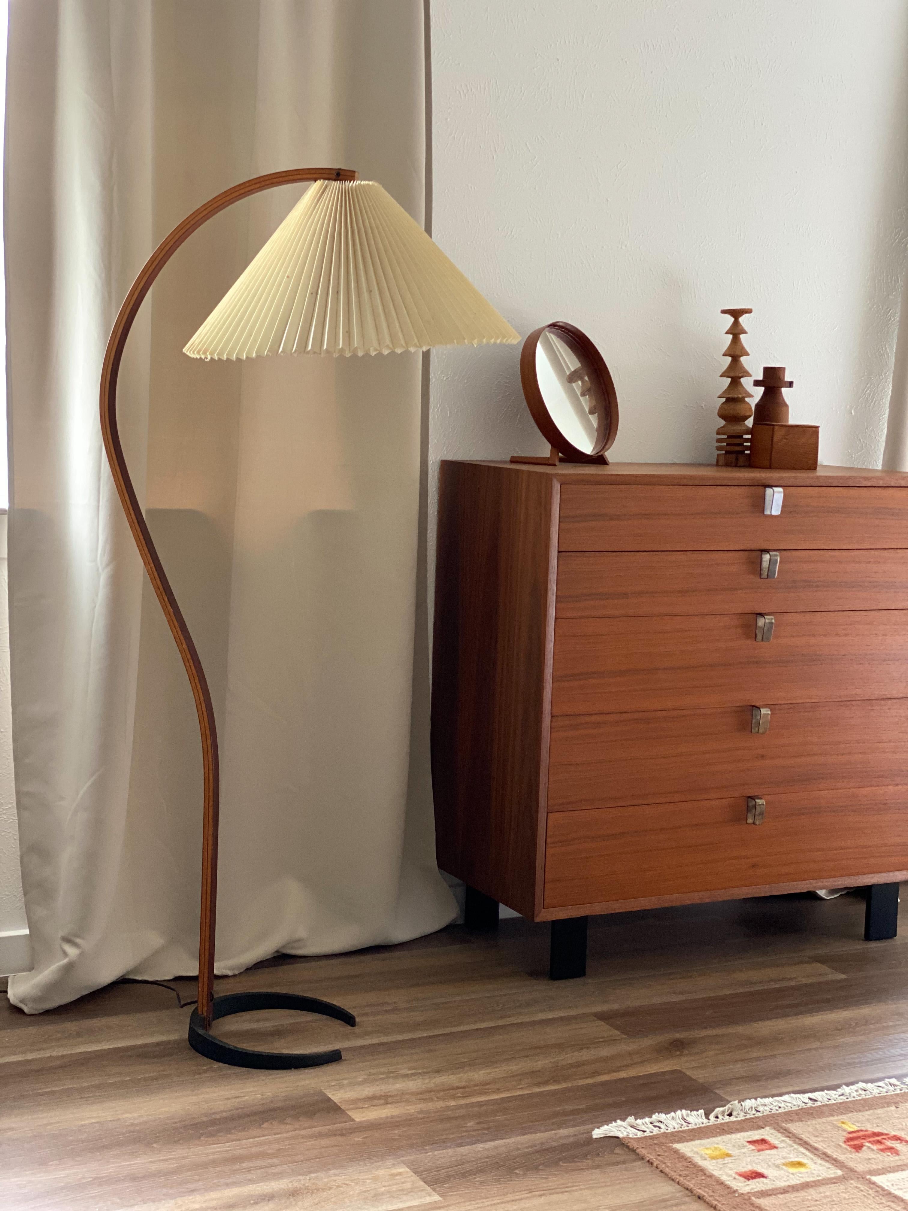 Early sculptural teak floor lamp designed by Mads Caprani Denmark, c. 1971. Iconic organic bentwood design complimented by its soft lighted pleated shade and crescent iron base. The shade is original and has staining, fraying and creases. We tried
