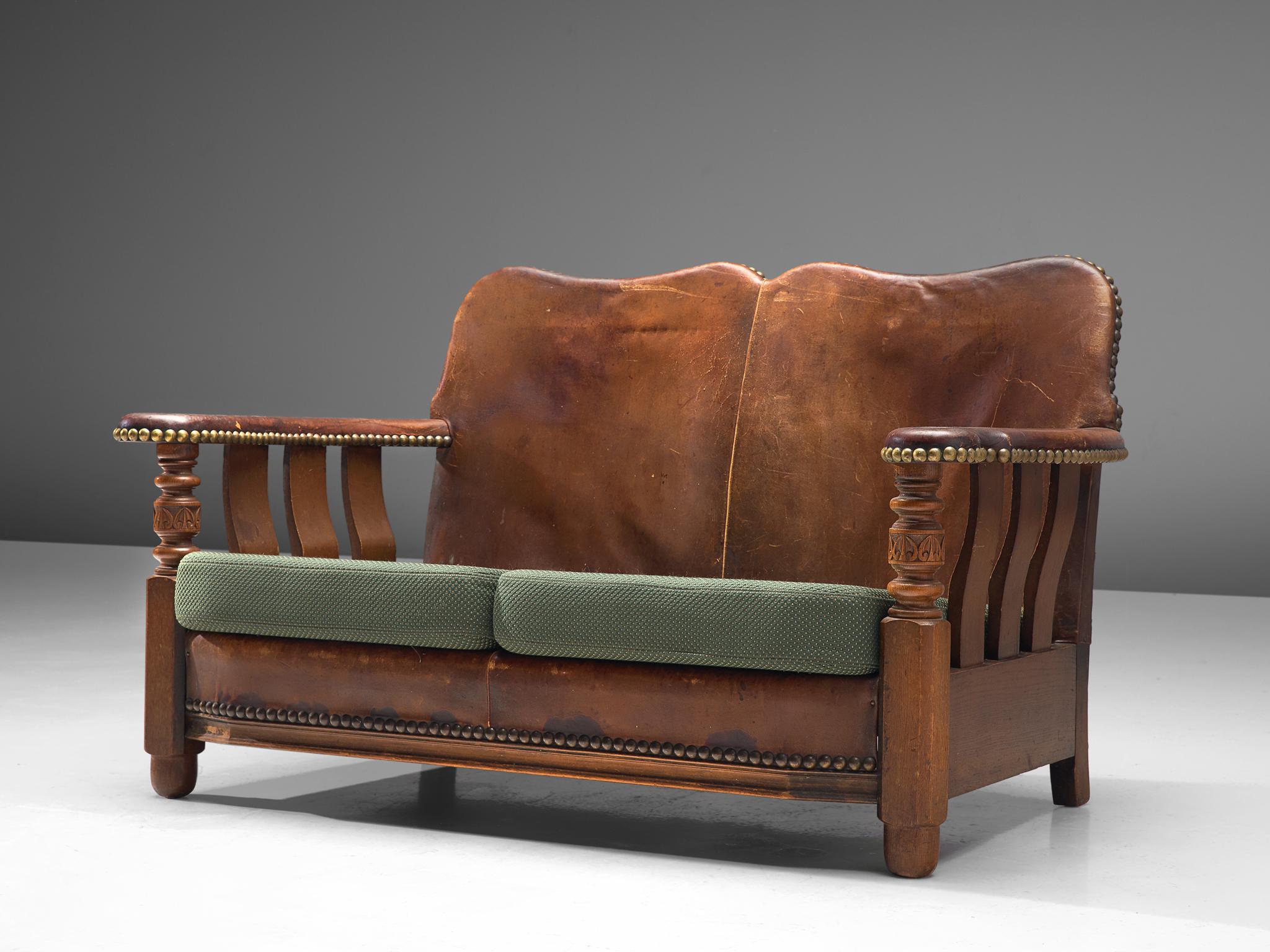 Settee or sofa, stained wood, leather, fabric, brass, Denmark, 1920s.

Exceptional example of early Danish design with robust, bulky aesthetics. The frame of the settee is made of stained wood. The back and armrests are upholstered with nail fitted,