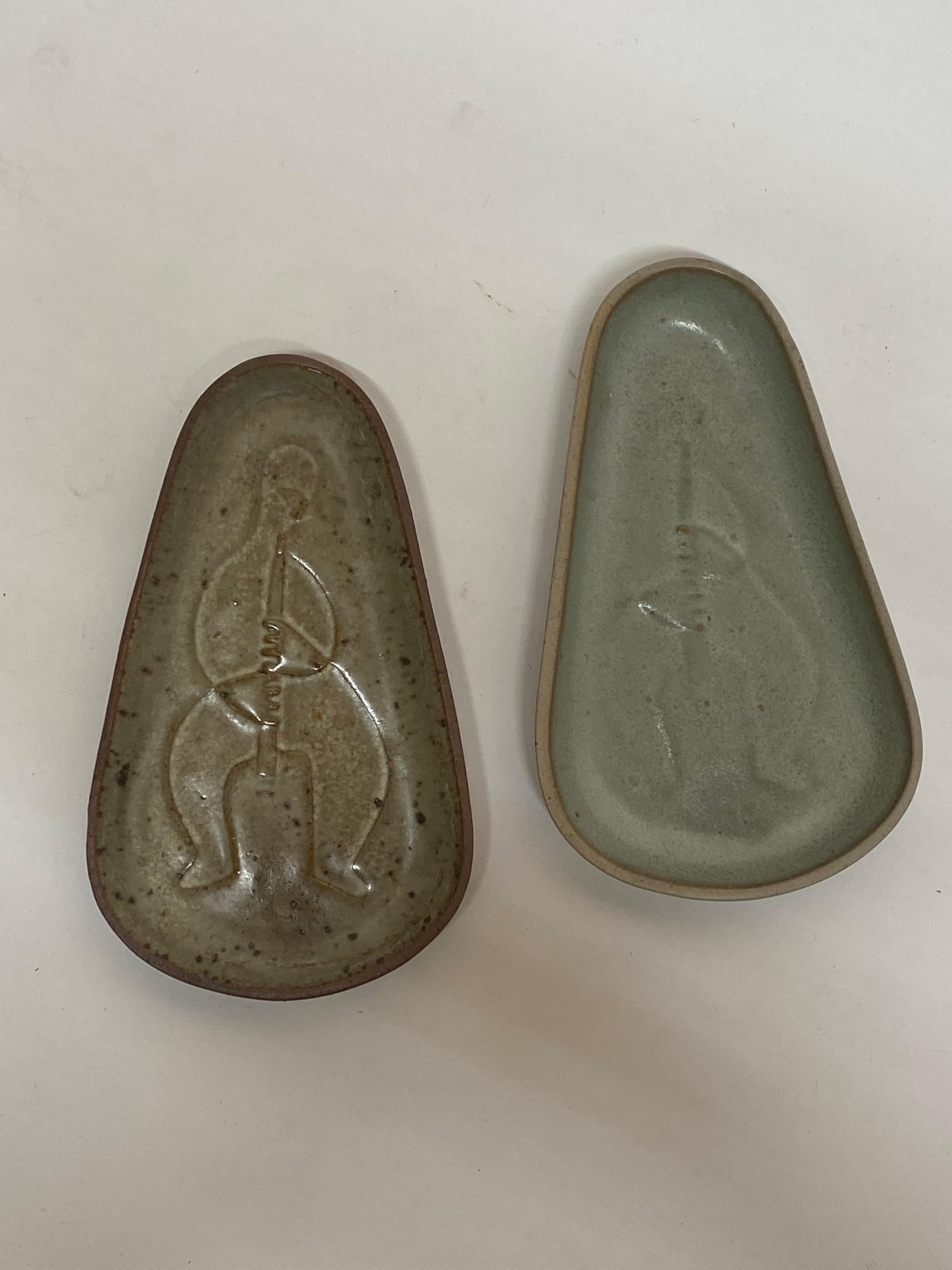 A pair of fine and early Bennington Potters triangular trinket trays. Signed on the reverse with early COOP and hand and face cipher mark. This mark apparently pre-dates the spark/forearm and hand stamp. The line image of the clarinet player (?) is