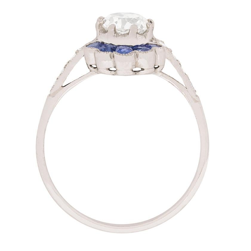 This unique and interesting ring dates back to the 1920s. The centre diamond is an old cut which weighs 0.70 carat and is estimated as G in colour and VS2 in clarity. Above and below are two sets of sapphires which are a deep blue. They are french