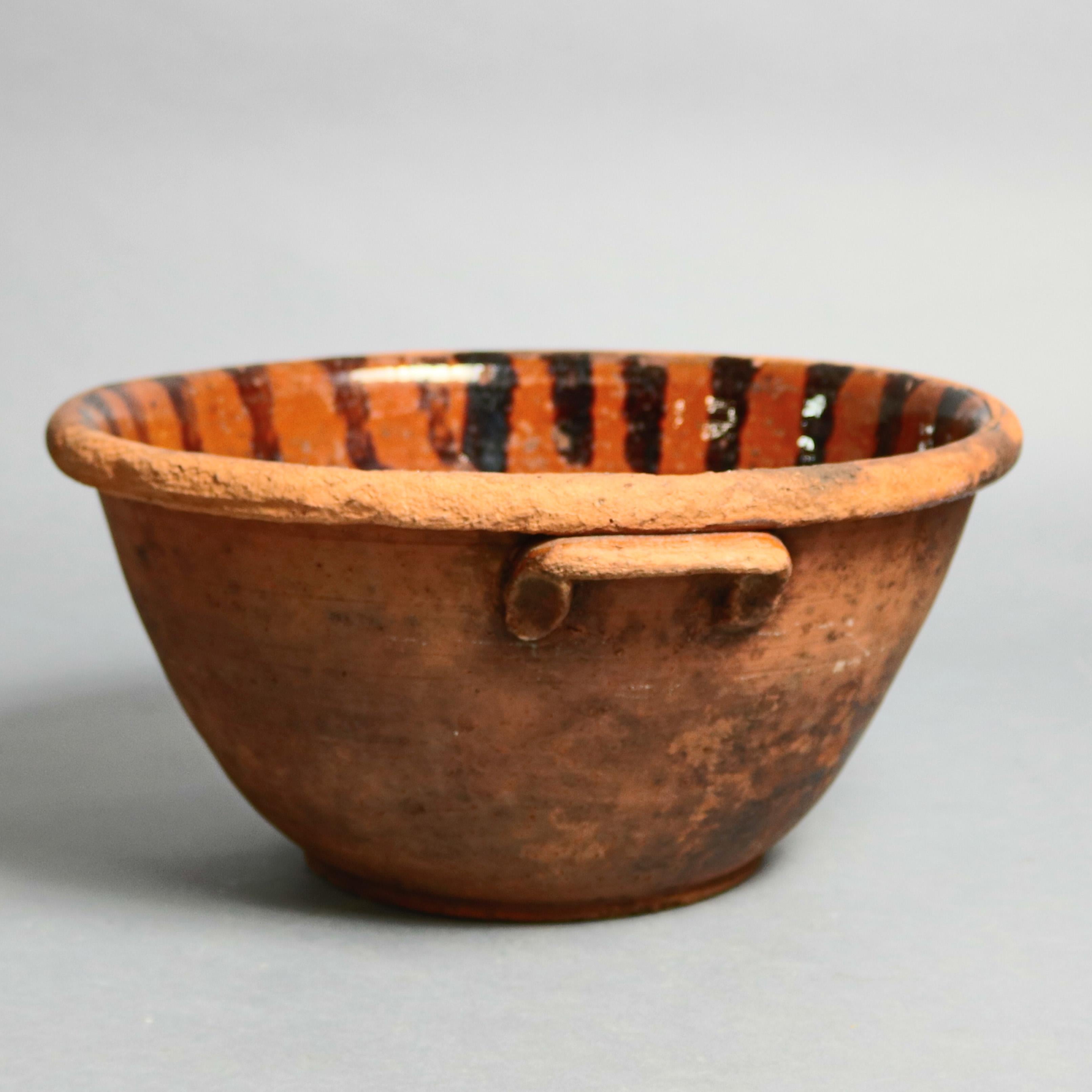 An early mixing bowl features redware construction in flared form with handles, interior hand decorated, circa 1840

Measures: 7.25