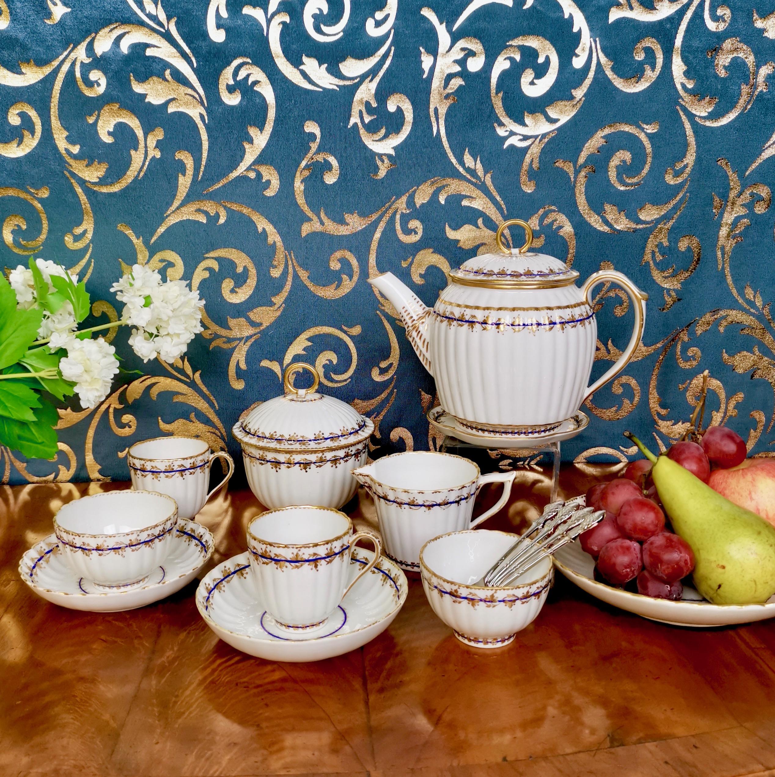 This is a very stunning porcelain breakfast set (also called Tête à Tête) made by the Crown Derby Porcelain Company some time between 1782 and 1800. It is made of white porcelain with a sophisticated gilt decoration. The set consists of a teapot
