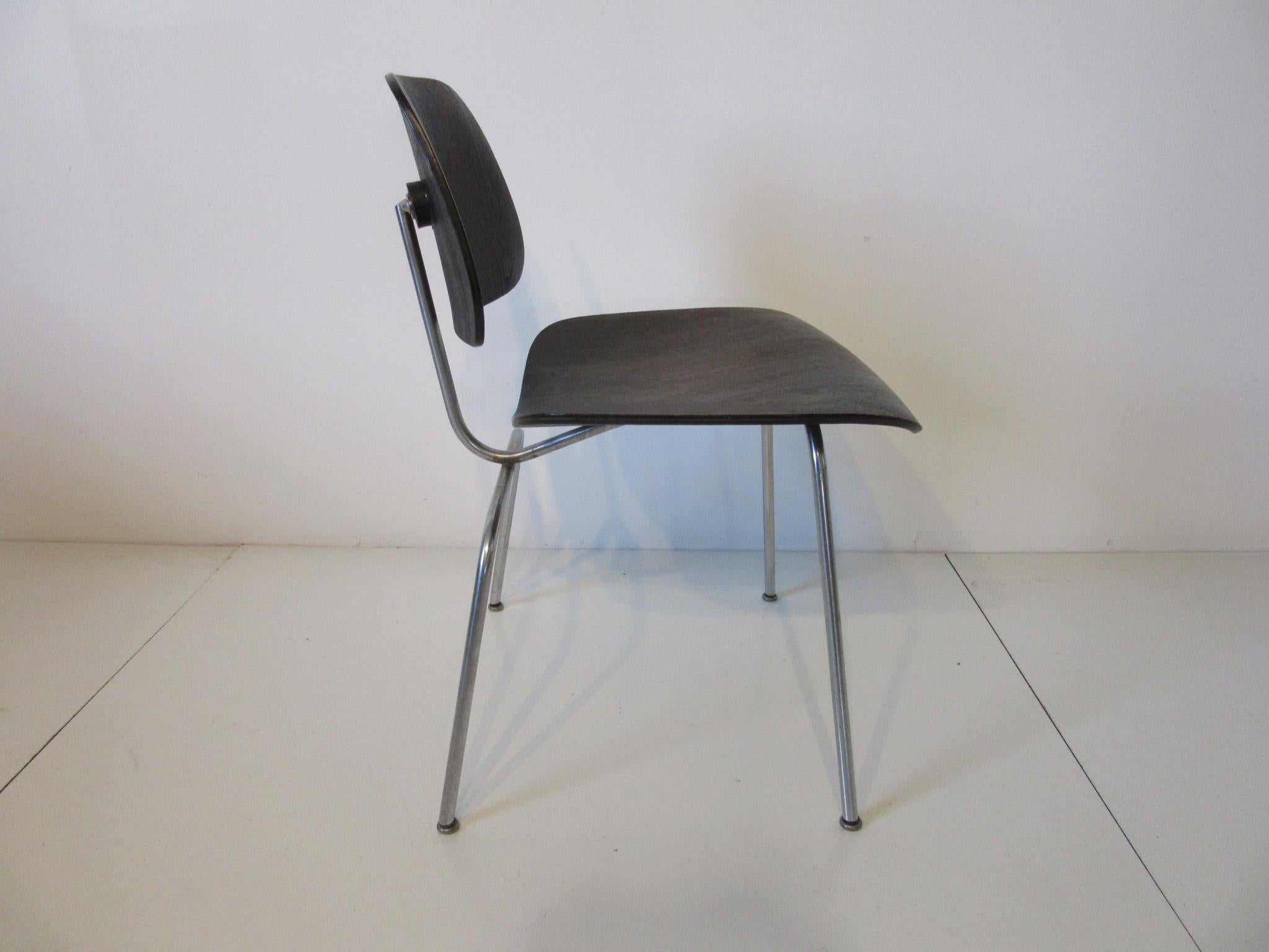 Sitz und Rückenlehne aus schwarzem, anilingefärbtem Holz, DCM (dining chair metal), verchromter Metallrahmen, kuppelförmige, stille Fußpads und frühes Folienetikett. Herman Miller Label entworfen von Charles Eames.