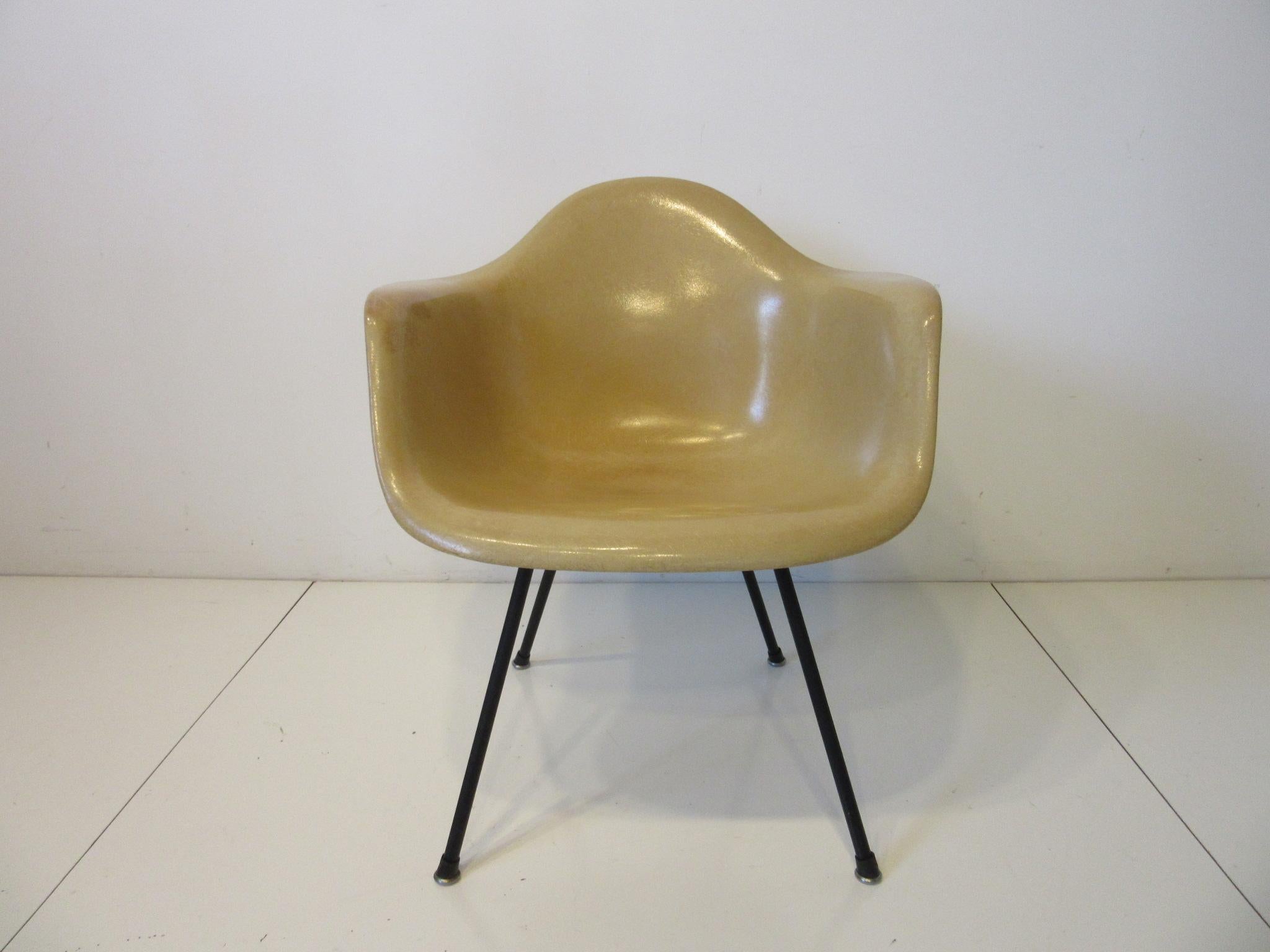 An early second generation Eames fiberglass arm shell chair with the large shock mounts, washers and a cast iron X-base in the rare lower lounge height. Manufactured by the Herman Miller Furniture company.