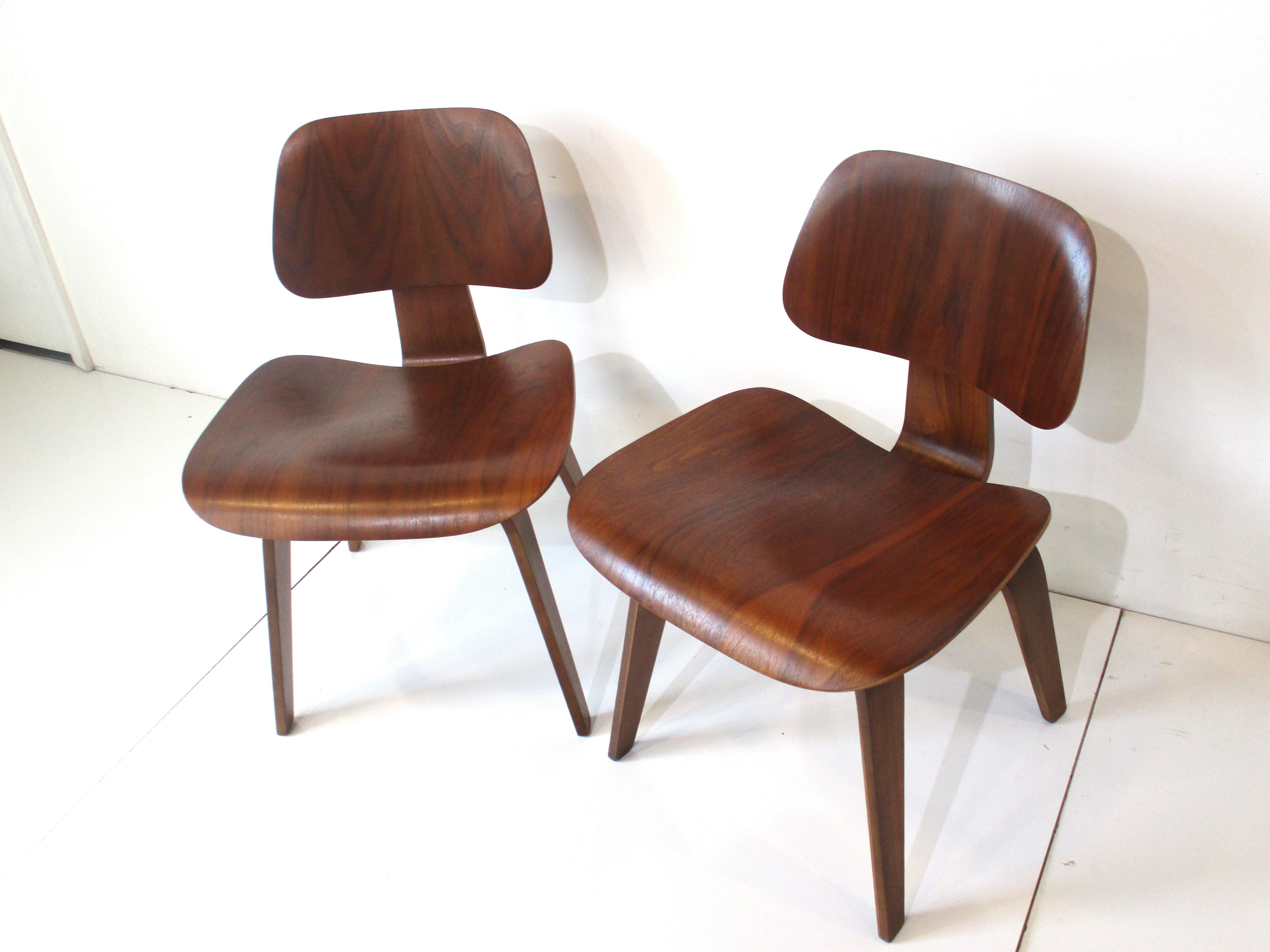 A pair of very well grained early bent walnut plywood side chairs designed by the iconic team of Ray and Charles Eames . These sculptural chairs are part of furniture history beginning after WW2 in which war production and peace time designs and