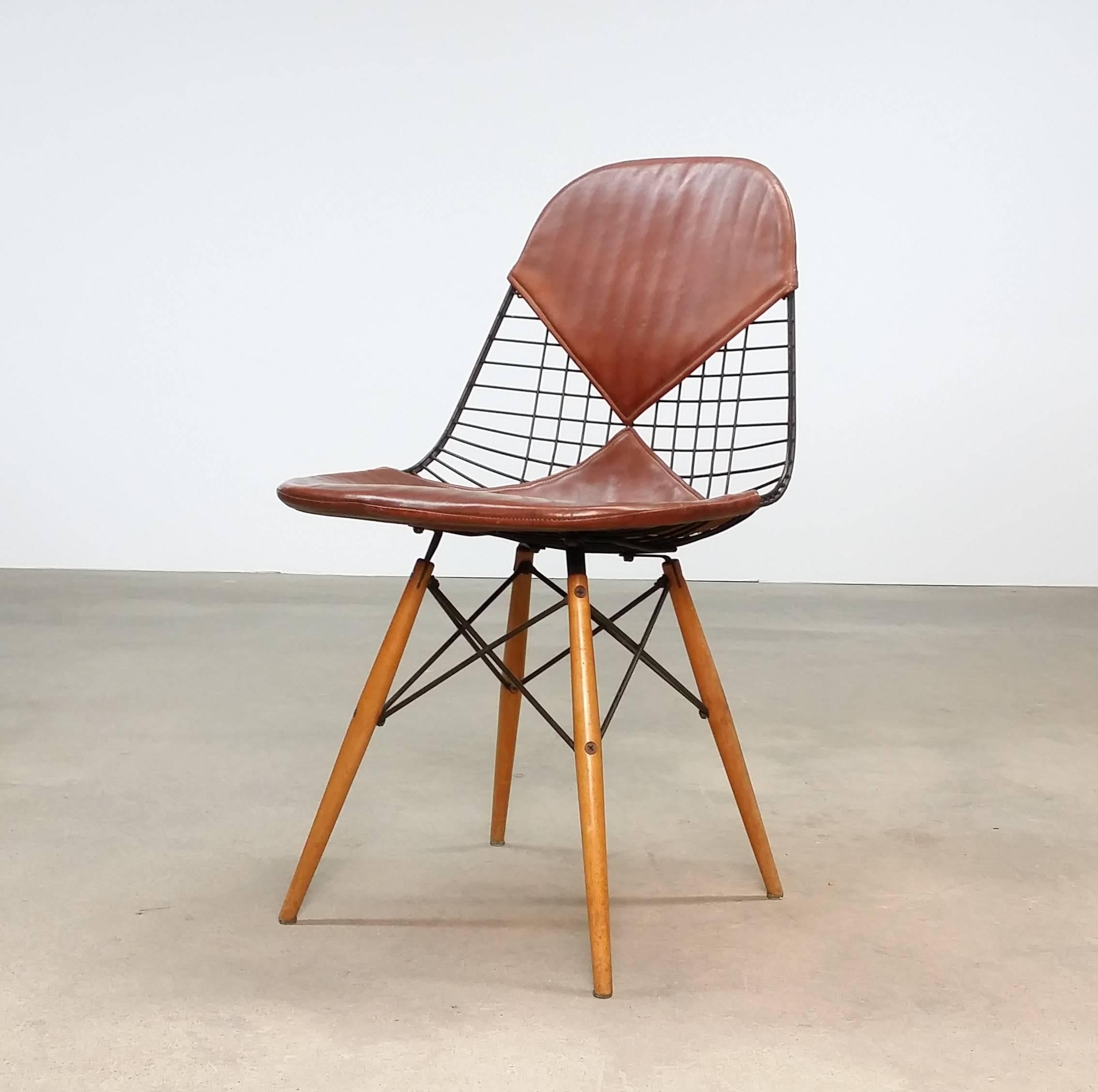 Early DKW-2 (dining height / wire shell / wood base) with leather bikini cover, designed by Ray & Charles Eames, circa 1950. This example produced by Herman Miller, circa 1952-1954. Retains the 901 West Washington Blvd, Venice California tag.