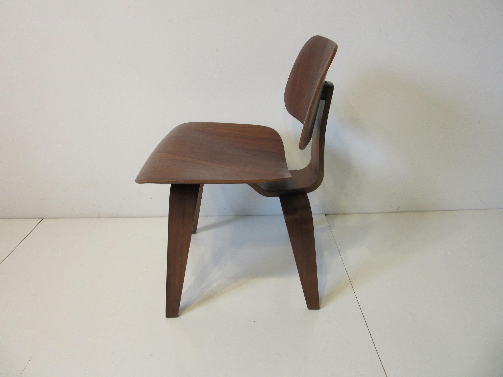 A sculptural DCW with flamed dark walnut graining to the seat and back giving this chair a rich wow factor, this early production chair has the five screw pattern to the bottom. A mid century iconic design from the team of Ray and Charles Eames