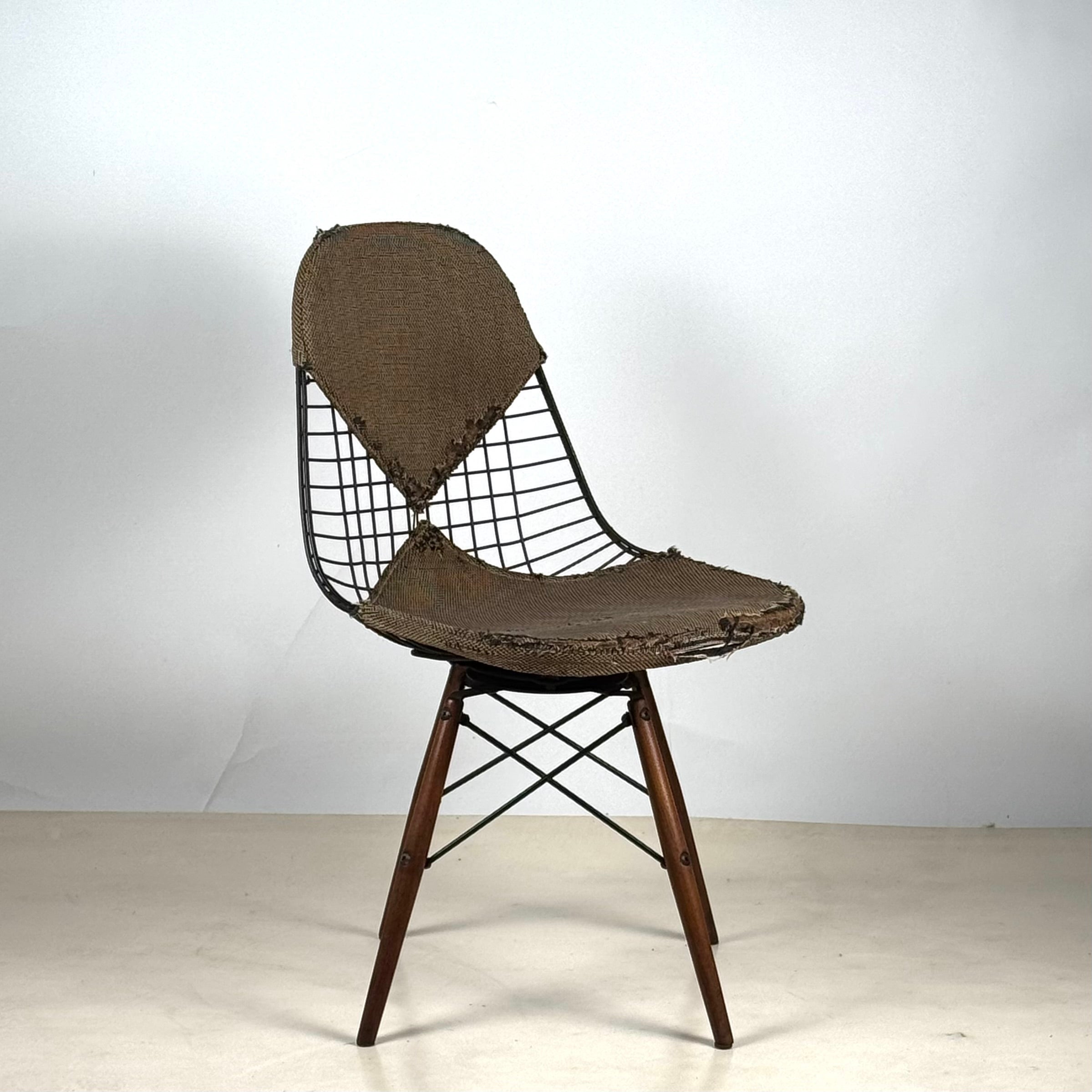 Rare early swiveling dowel leg chair with walnut legs, designed by Charles & Ray Eames for Herman Miller, model DKW-1, 1951/1952.
Wire top and timeworn weaved fabric seat.
Original tag.
Museum quality.