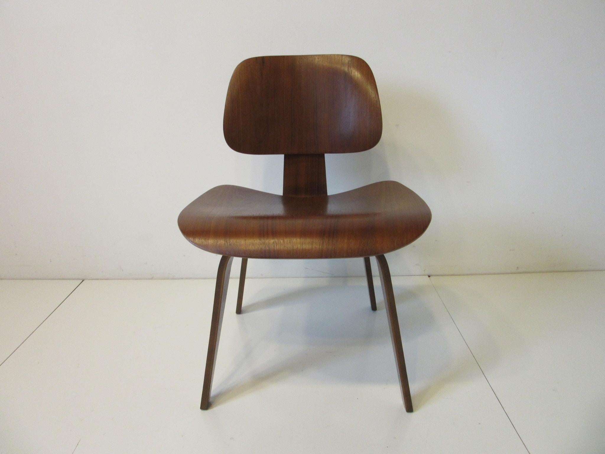 A very early nicely grained walnut DCW sculptural side chair designed by the husband and the wife team of Charles and Ray Eames. This iconic piece of mid century furniture history produced in the 1950's still feels as fresh today as it did then.