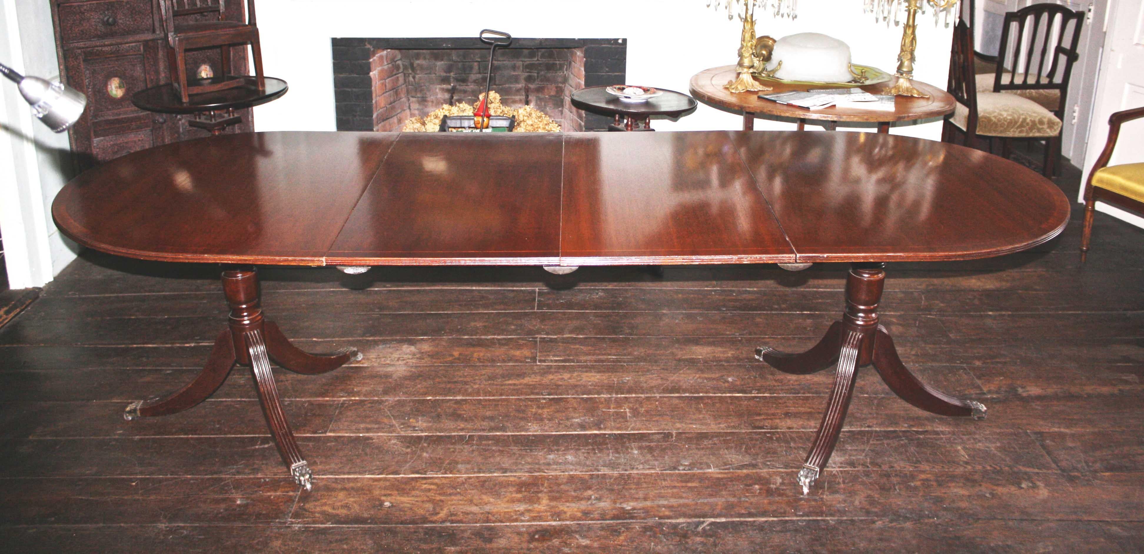 George III revival demilune-ended, banded with string inlay and reeded table-top edges.
Reeded legs, six brass paws with casters. Just 39 inches wide; the two leaves are each 
20 inches and provide perfect comfortable seating for eight. An ideally