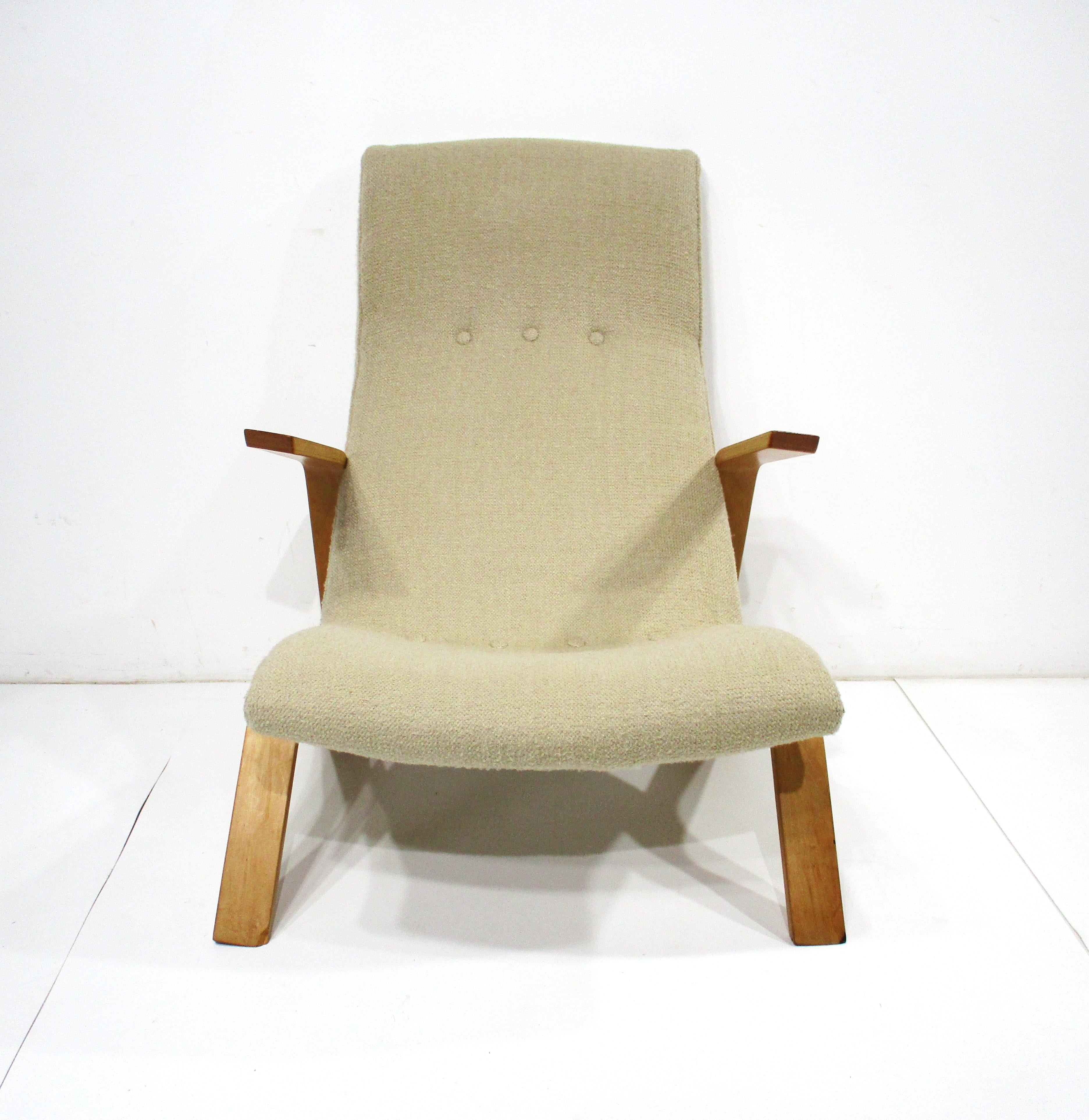 A early production Grasshopper lounge chair with nice sculptural arms and leg design . The upholstery is a mellow oatmeal color with the butter scotch birch arms making quite the statement . The chair is very comfortable with the slanted arms and