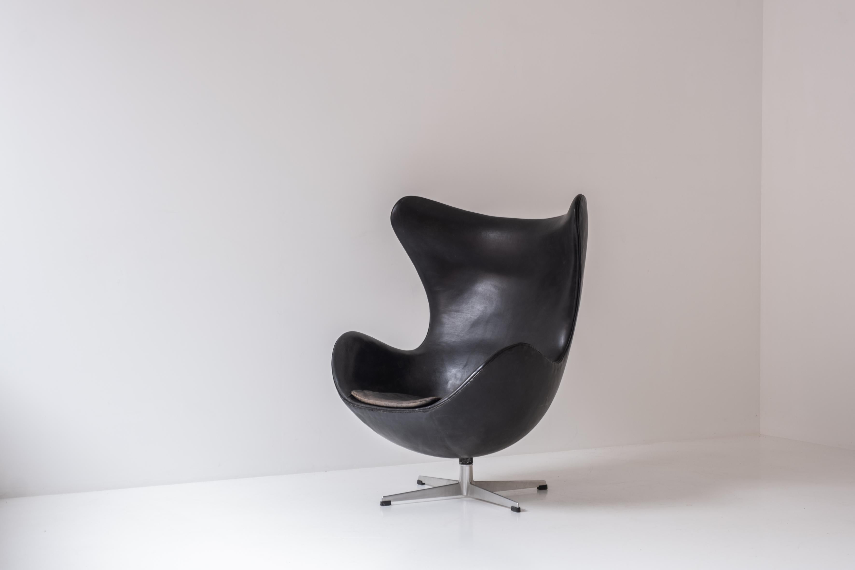 Early ‘Egg’ armchair by designed by Arne Jacobsen for Fritz Hansen, Denmark 1958. This piece features the original black leather upholstery and the first edition alumium base. Arne Jacobsen designed and built the Royal Hotel in Copenhagen and also