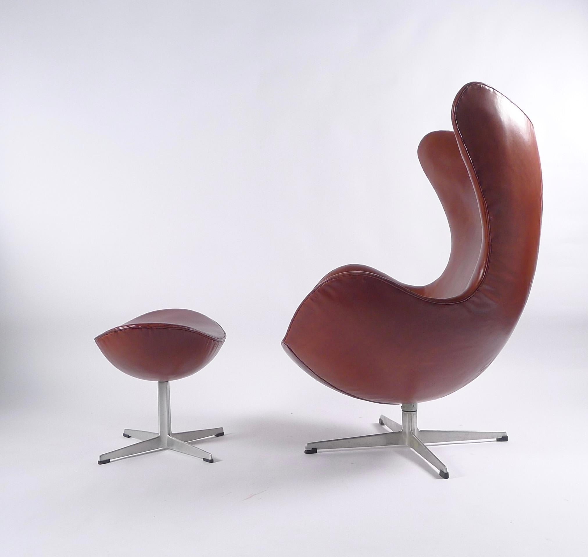 Iconic egg chair and matching ottoman, upholstered in rich cognac leather. 

This iconic chair was designed by Arne Jacobsen in 1958 as part of a commission to furnish the interior of the SAS Hotel in Copenhagen, Denmark. These chairs were placed