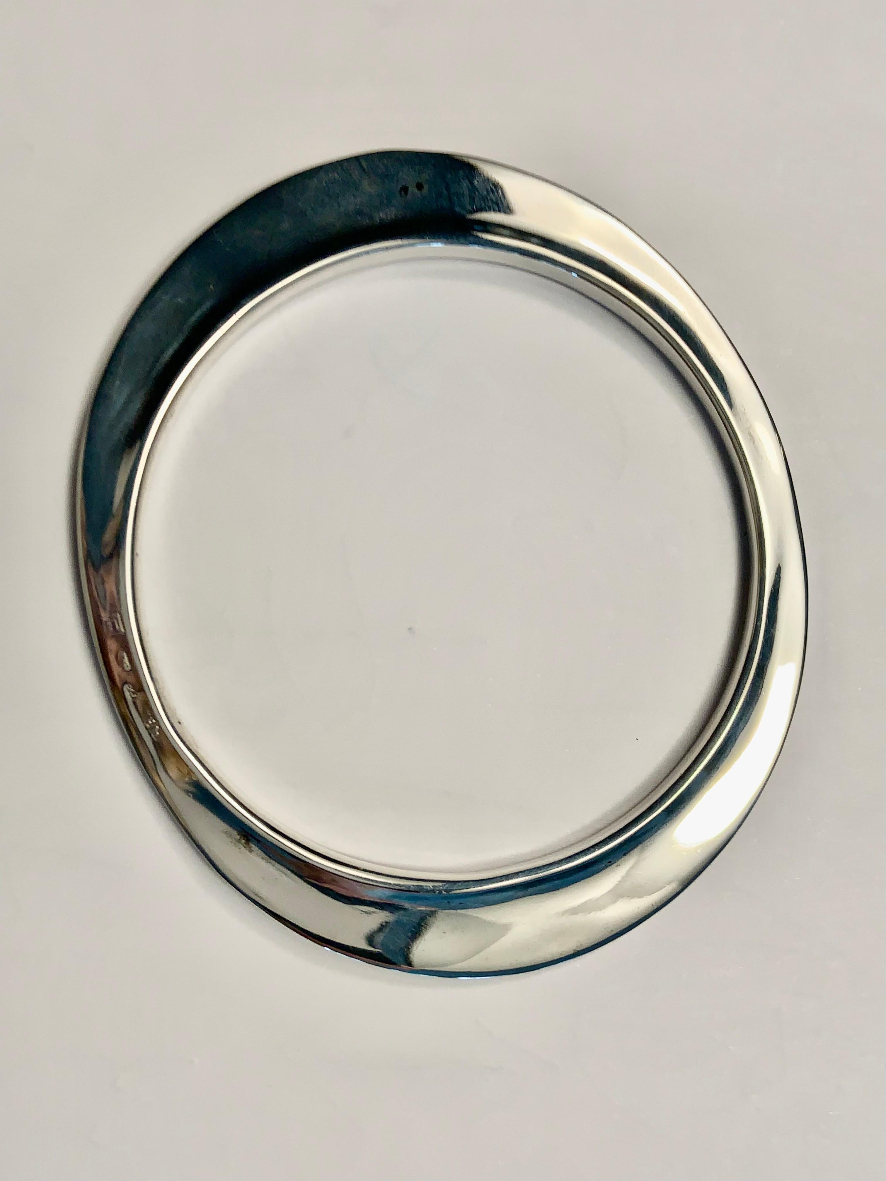 This flying saucer bracelet is from the very early days of the Elsa Peretti and Tiffany & Co partnership.  It is marked E for Elsa Peretti, 925 and T& Co.  The oval bracelet has a raised lip at the center opening and it is wider on the two long ends