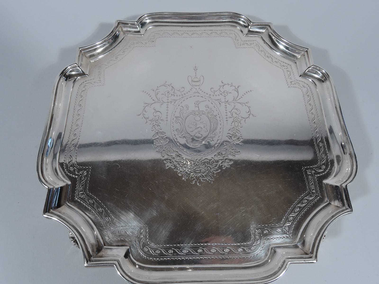 George II sterling silver salver. Made by John Tuite in London in 1727. Four-sided cartouche with concave corners and molded rim. Four leaf-capped volute scroll supports. Well has engraved central armorial with Amphora and garland as well as