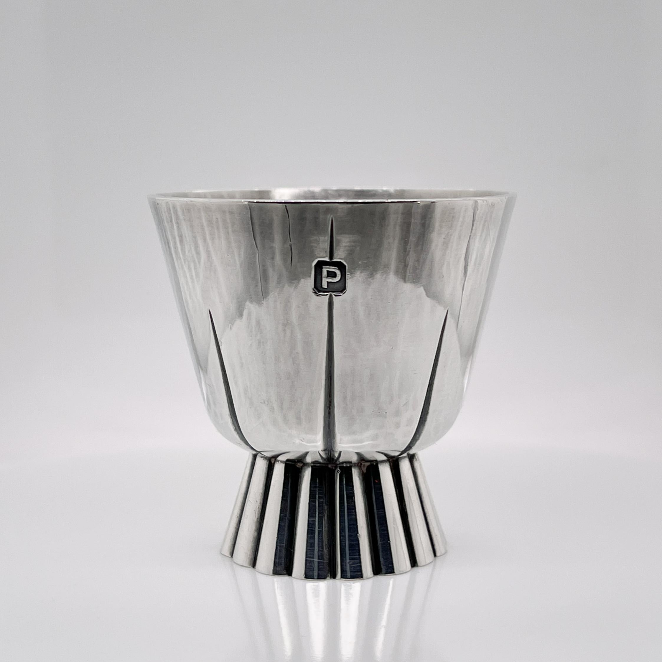 A fine English sterling silver diminutive cup or shot glass.

By the contemporary English silversmith Adrian Gerald Sallis Benney. 

This work is marked with a hallmark for 1950, which is very early in the work-life of Gerald Benney. 

Simply an