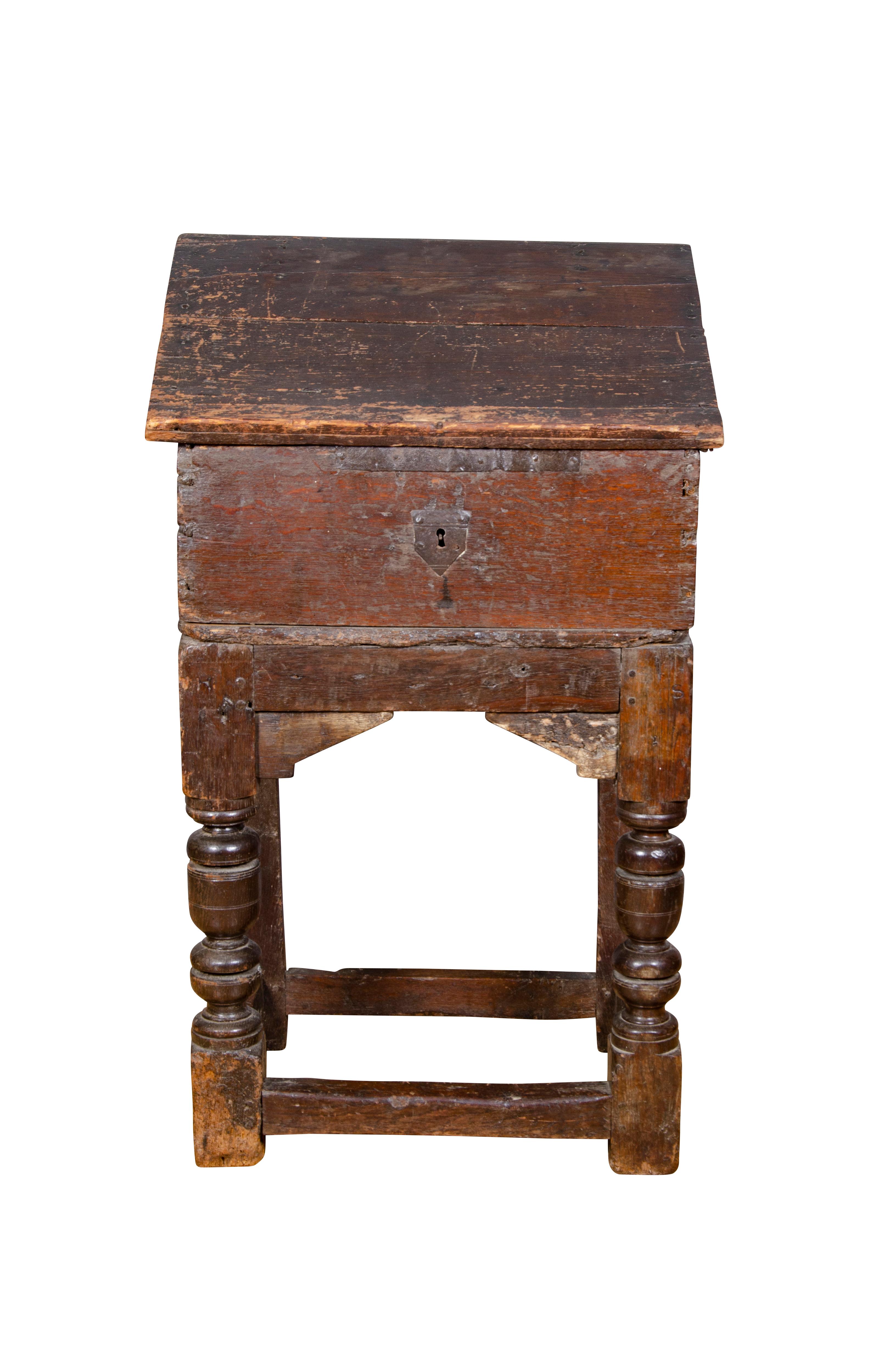 With a hinged slant lid opening to a compartment, raised on turned legs joined by a box stretcher. Provenance; J.P Morgan.