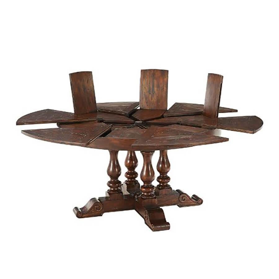 An Early English style round extension dining table with antiqued wood, the circular top of parquetry panels with six pull-out sections revealing self-storing fold-out leaves, above four baluster turned supports, on a crossover scroll foot base. The