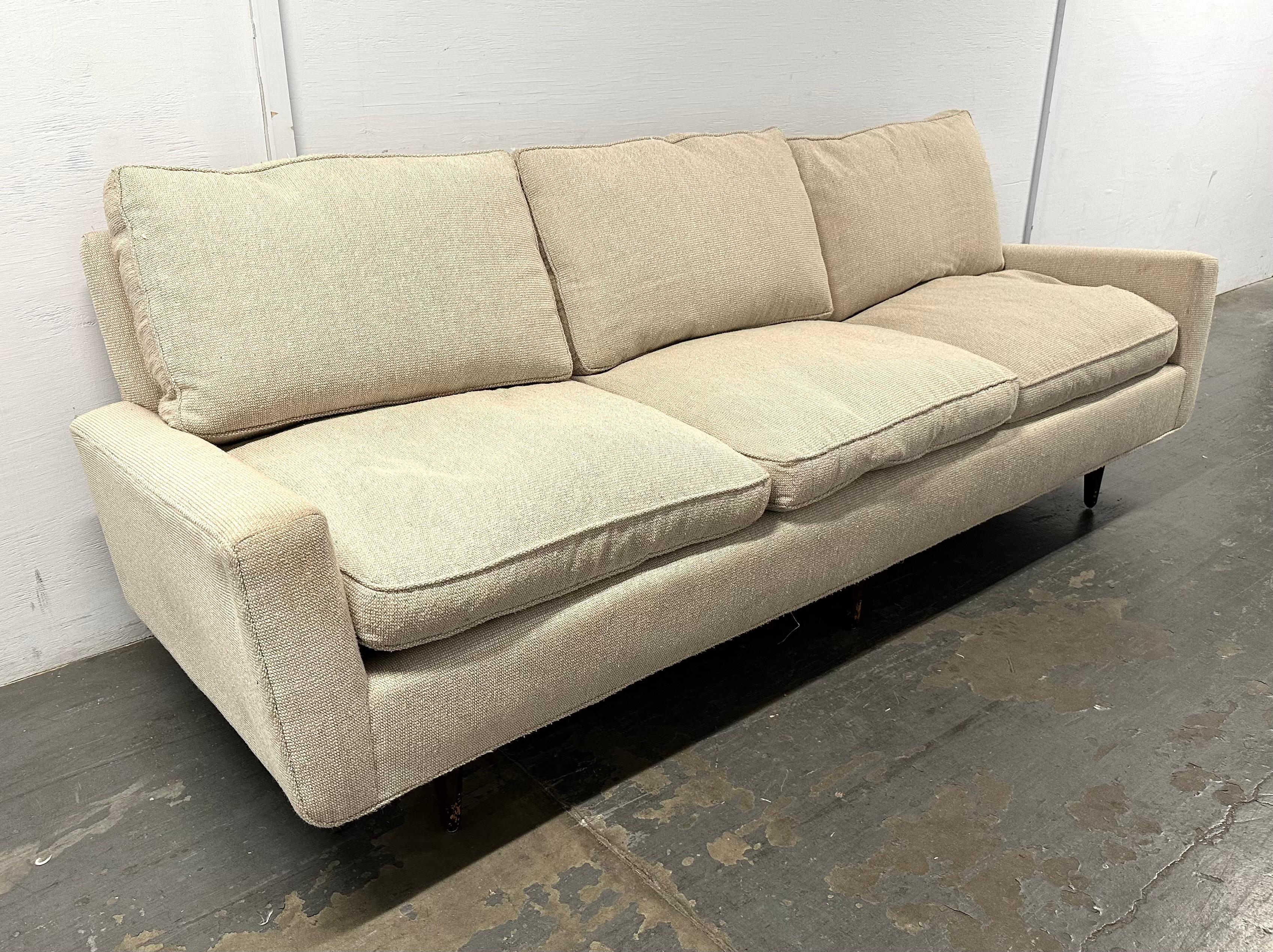 Sehr frühes Florence-Knoll-Sofa, ca. Ende der 1940er Jahre, in altem, haferflockenfarbenem, genopptem Knoll-Wollstoff, mit Daunen-Sitz- und Rückenkissen. Durch die sechs eingesetzten Beine scheint das Sofa zu schweben. Der Rahmen aus Hartholz und