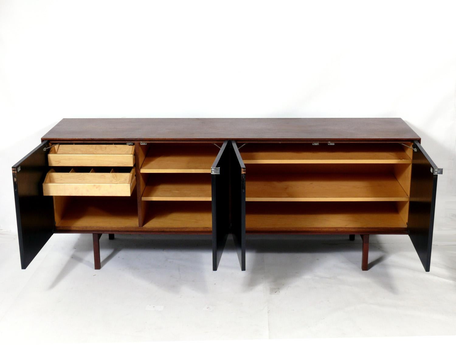 Clean lined walnut and black lacquered credenza, designed by Florence Knoll for Knoll, circa 1950s. Signed with early Knoll tag underneath. This piece is a versatile size and can be used as a credenza, TV/Media cabinet, bar, or server in a living