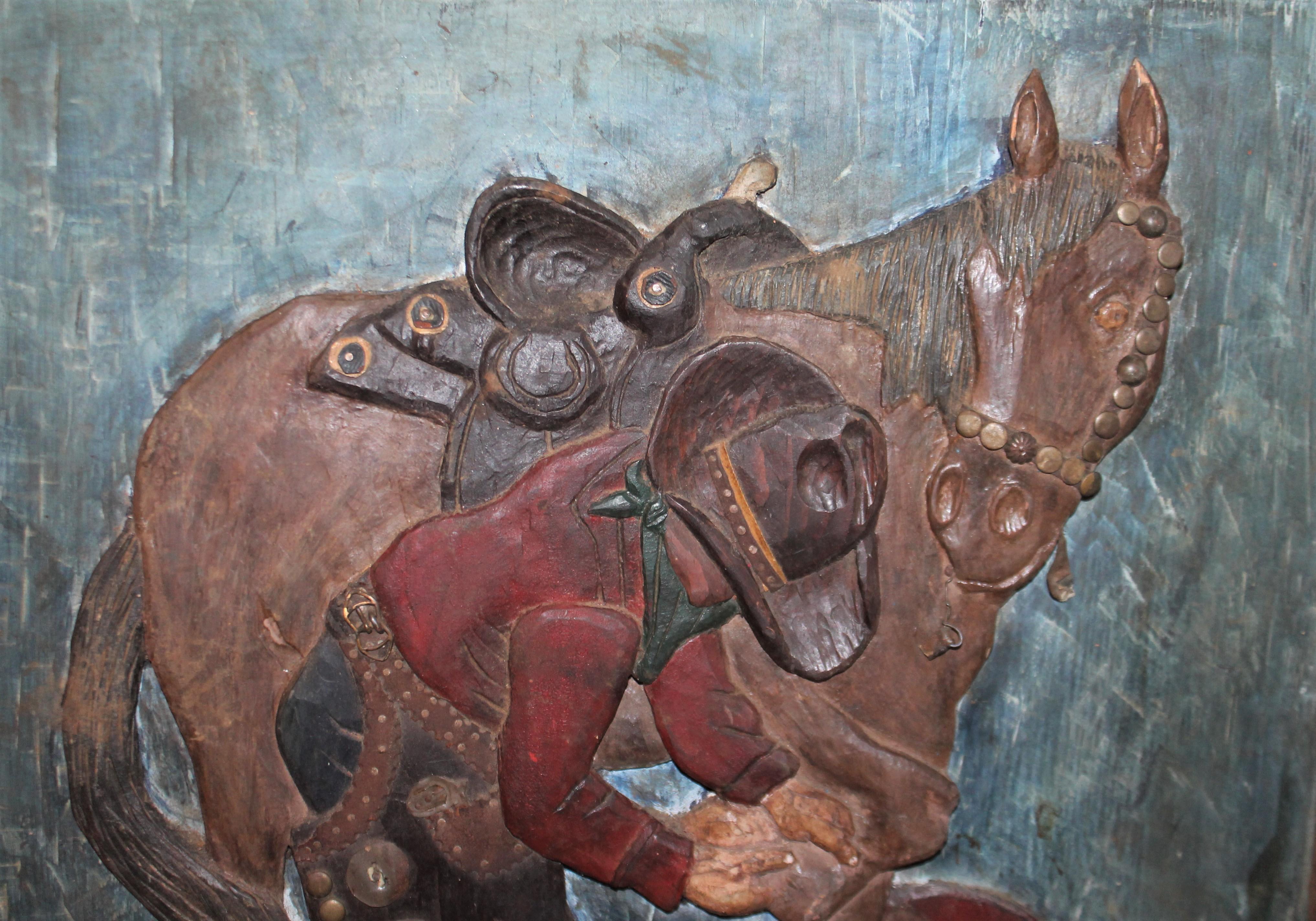 Cette sculpture en relief d'art populaire, sculptée et peinte à la main, représente un cow-boy avec son cheval. Il est entièrement peint d'origine et son cadre original est sculpté et peint à la main. Cette sculpture folklorique peinte a une surface