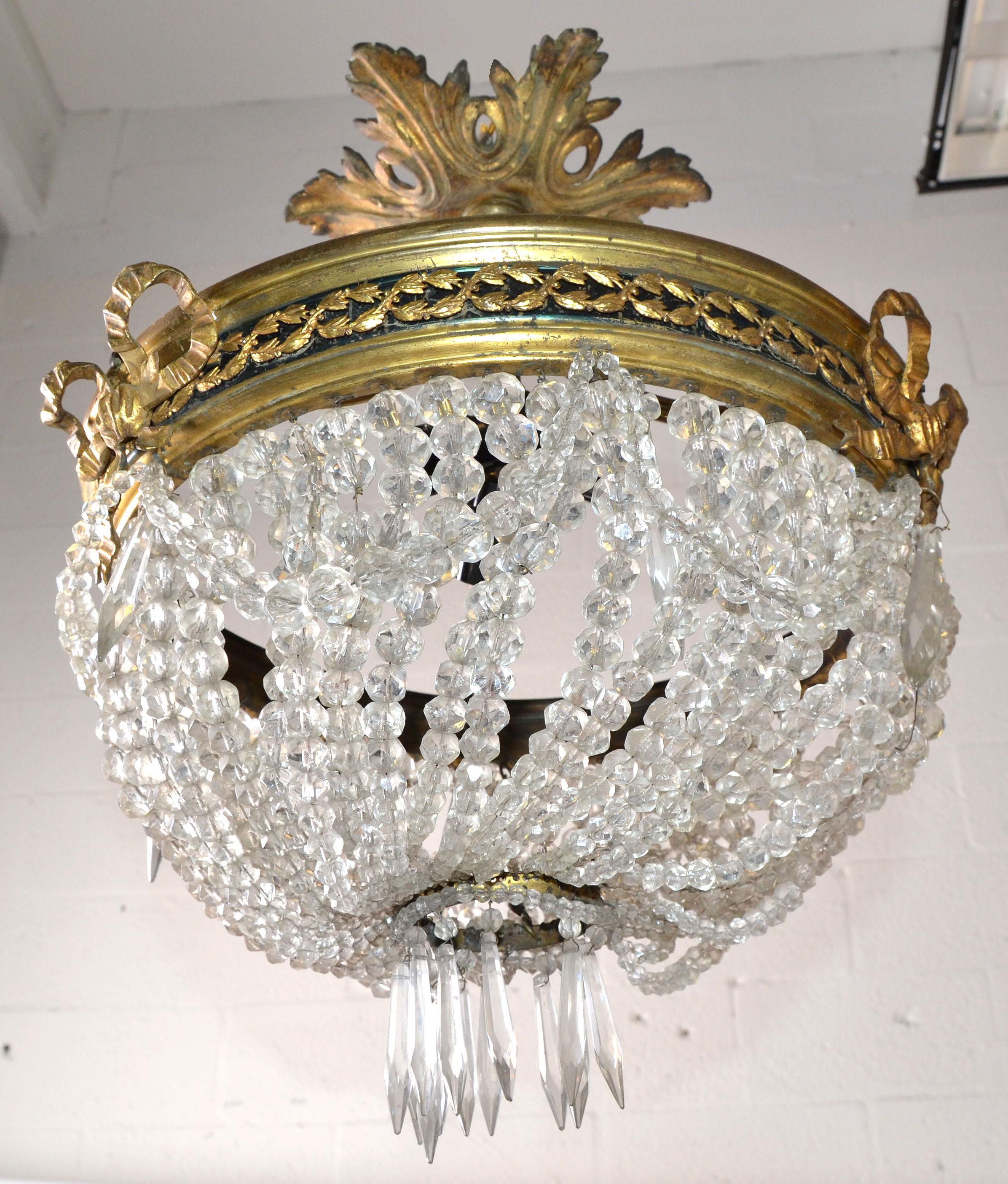 Empire Style early round Bronze and Crystal Chandelier with 3 Light-sockets in the center. 
Wired for the US and takes 3 candelabra light bulbs max. 60 watts.
In original vintage condition with some losses to the brass bows and a few crystals.