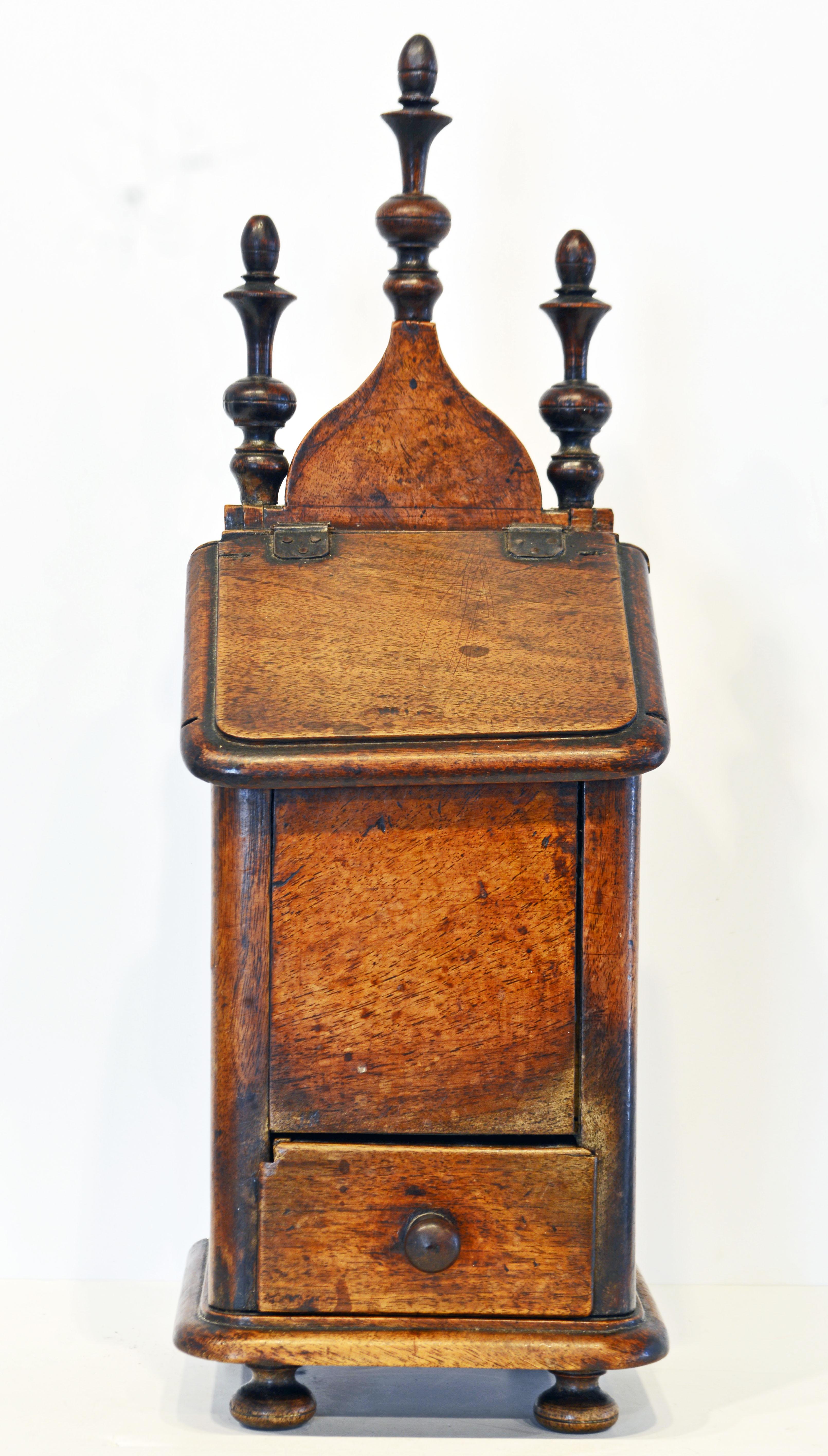 Authentic French Provincial walnut salt box or 'boite s sel' dating to circa 1830. It features a Gothic style pediment adorned by three turned finials above an iron hinged slanted lid and a small drawer standing on four turned bun feet. The box has