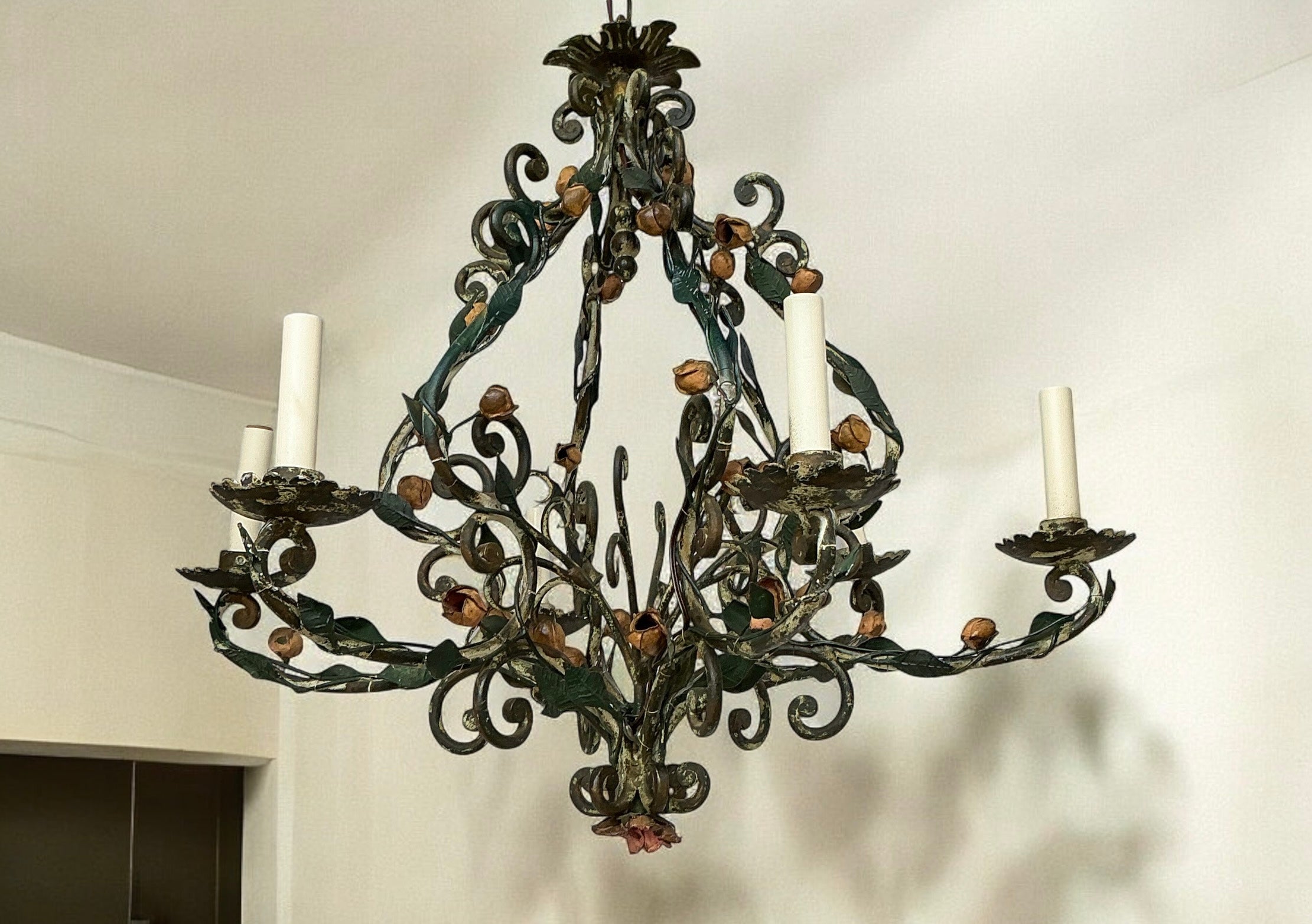 This is an early 20th century French iron six arm chandelier with cascading leaves and roses. It has six arms and the wiring is new. Age appropriate wear typical of tole. 

This will be handled with white glove shipping or FedEx freight as it is