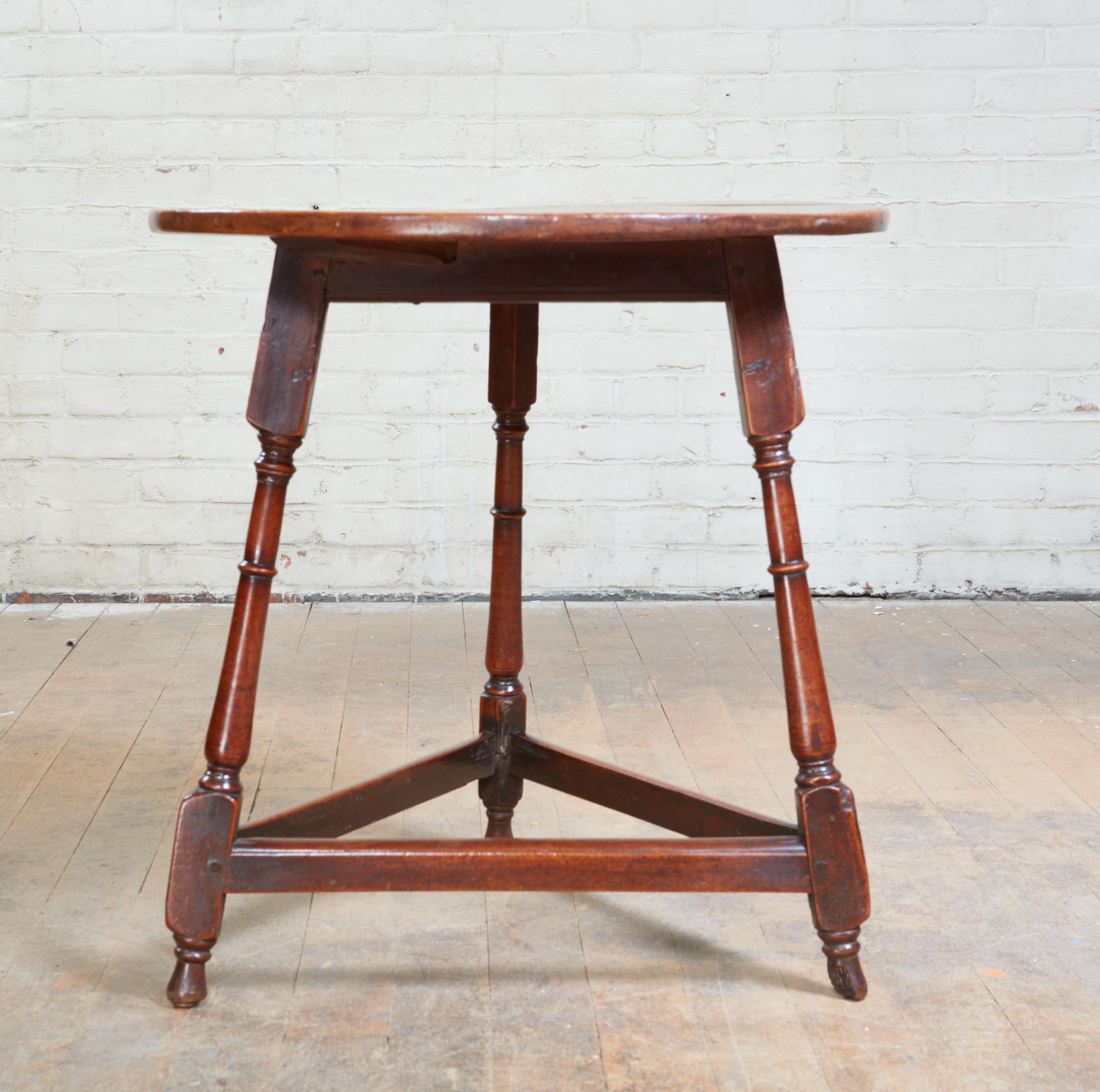 Good early 18th Century English or Welsh fruitwood cricket table, the well patinated top over three balustrade turned splayed legs joined by triangular box stretchers, and standing on original turned feet, the whole with excellent color and patina.