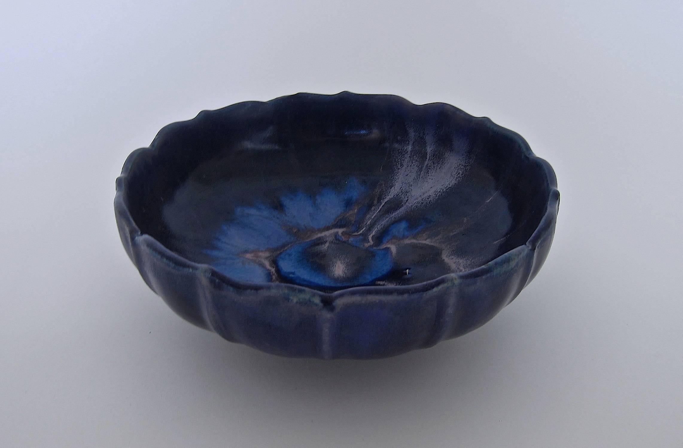 A vintage lotus form American art pottery footed bowl from Fulper Pottery of Flemington, New Jersey. The fluted bowl, sometimes called a fruit bowl, is decorated with a rich purple/blue/indigo glaze, accented with shades of lighter blue and hints of
