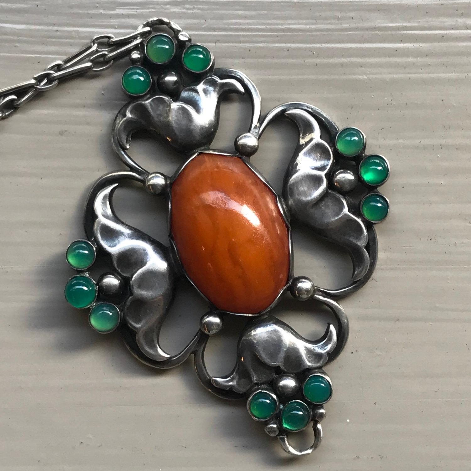 Early Georg Jensen 830 Silver Large Pendant  No. 40 with Amber and Chrysoprase

With original chain, 16.5’’  long, very good condition considering its age.

Designer: Georg Jensen
Maker: Georg Jensen
Design #: No.40
Circa: 1915-1919
Dimensions: