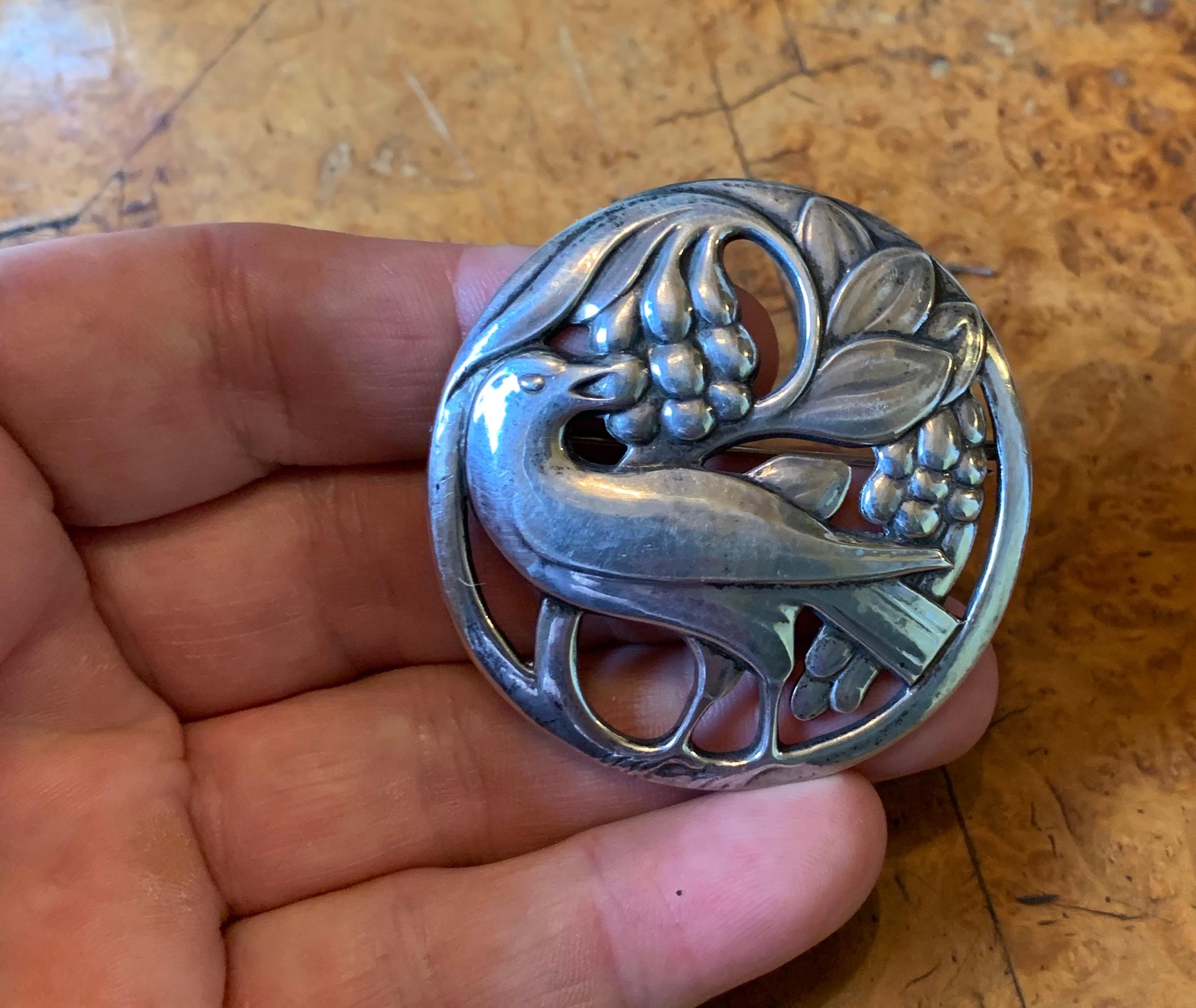 This is the large gorgeous early (1933-1944) Georg Jensen sterling silver pin brooch in the form of a bird eating berries with leaves in a gorgeous open work design.  The brooch has the early Jensen mark of JG in a rectangle and is number 53.
This