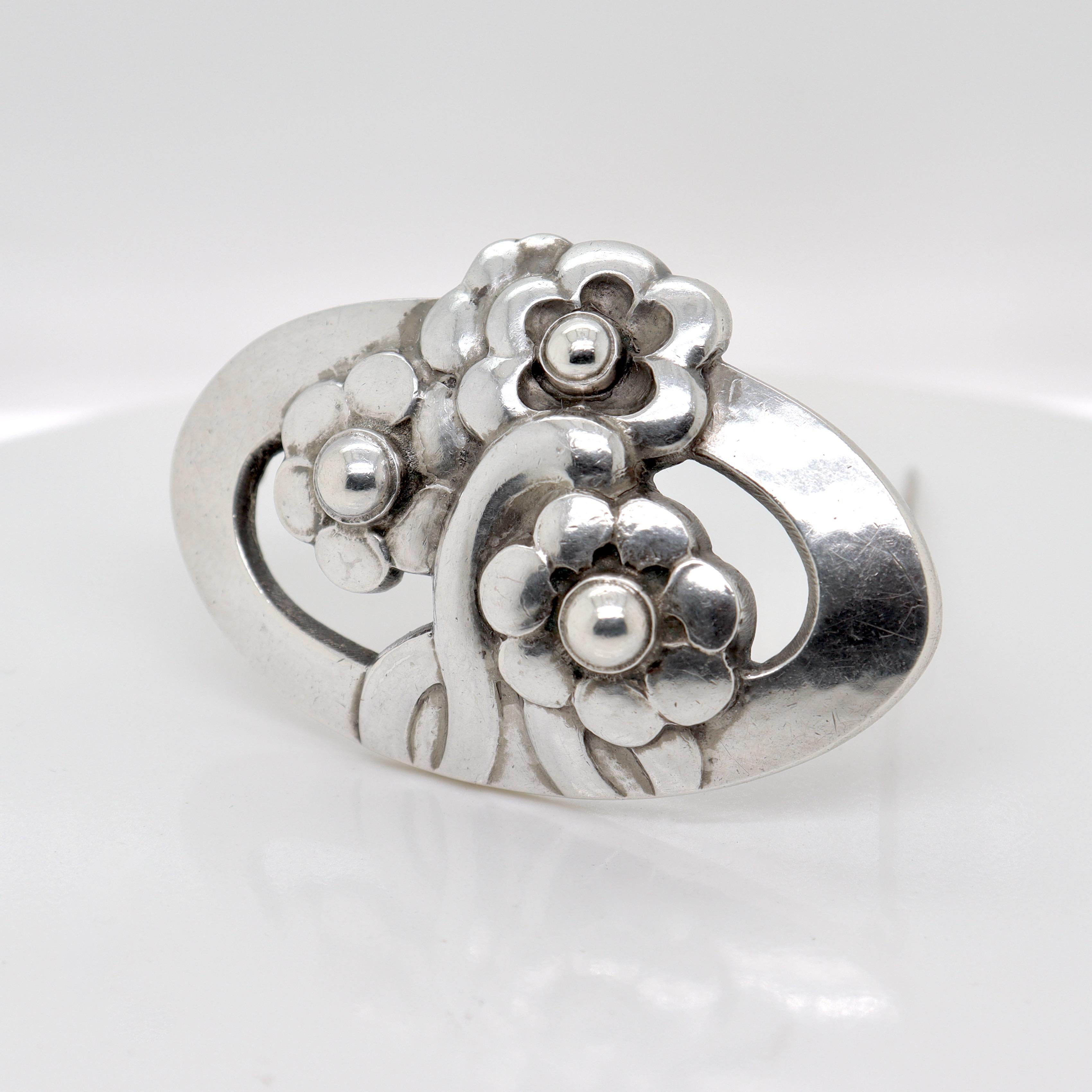 A fine Georg Jensen sterling silver pin or brooch.

Model no. 28.

Designed by Georg Jensen.

In the form of a hand-hammered, stylized flowers.

Simply a wonderful brooch from Denmark's premier silversmiths!

Date:
Early 20th Century,