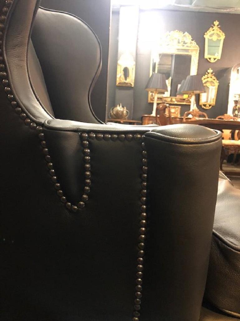 The raked back with a tablet shaped head rest to articulated wings sweeping to padded arms supported by cabriole leg to pad foot. The whole reupholstered in the traditional manner in black Verona leather.


 