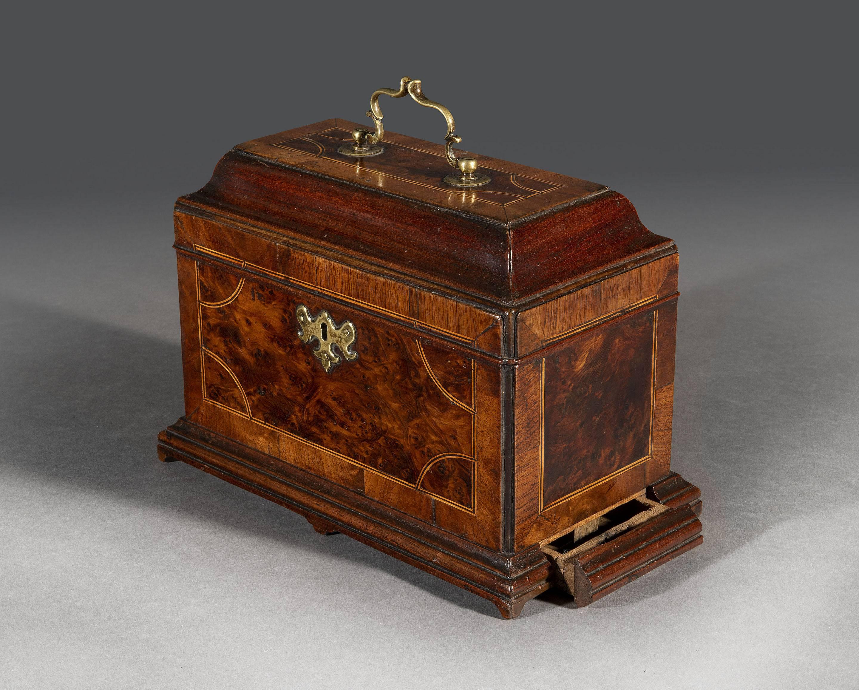 The brass mounted tea chest is fitted with the original metal tea containers and reveals a concealed spoon drawer. The walnut inlaid tea caddy stands on ogee bracket feet.