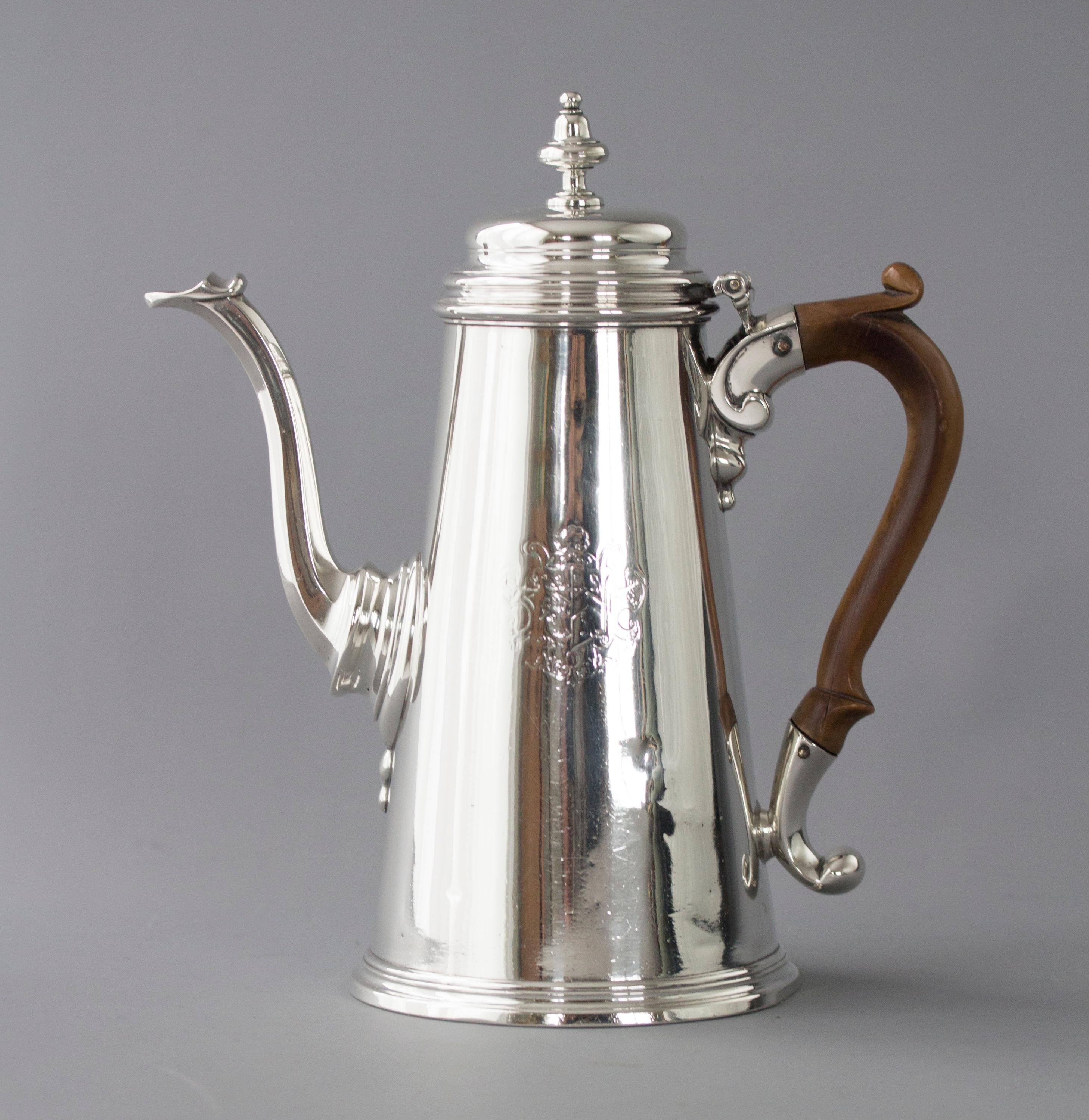 An early George II silver coffee pot. Of plain tapering form, with a raised, stepped lid topped with an acorn finial. Cast octagonal swan-neck spout, and a carved wooden handle set in scrolling mounts, all standing on a stepped based. Engraved to