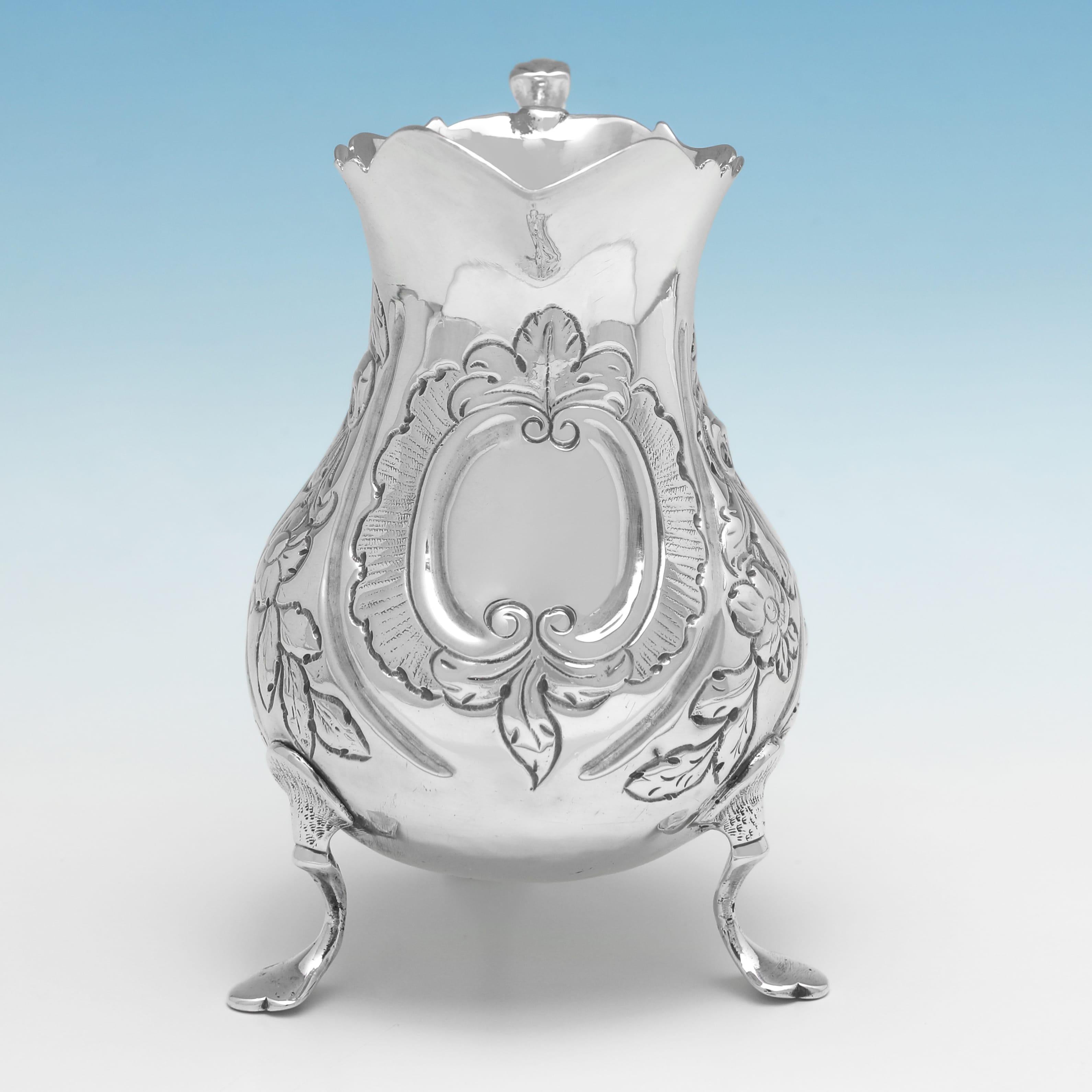 Hallmarked in London in 1763, this attractive, George III, Antique Sterling Silver Cream Jug, stands on three feet, and features later chased floral decoration to the body and an acanthus detailed handle. 

The cream jug measures 4