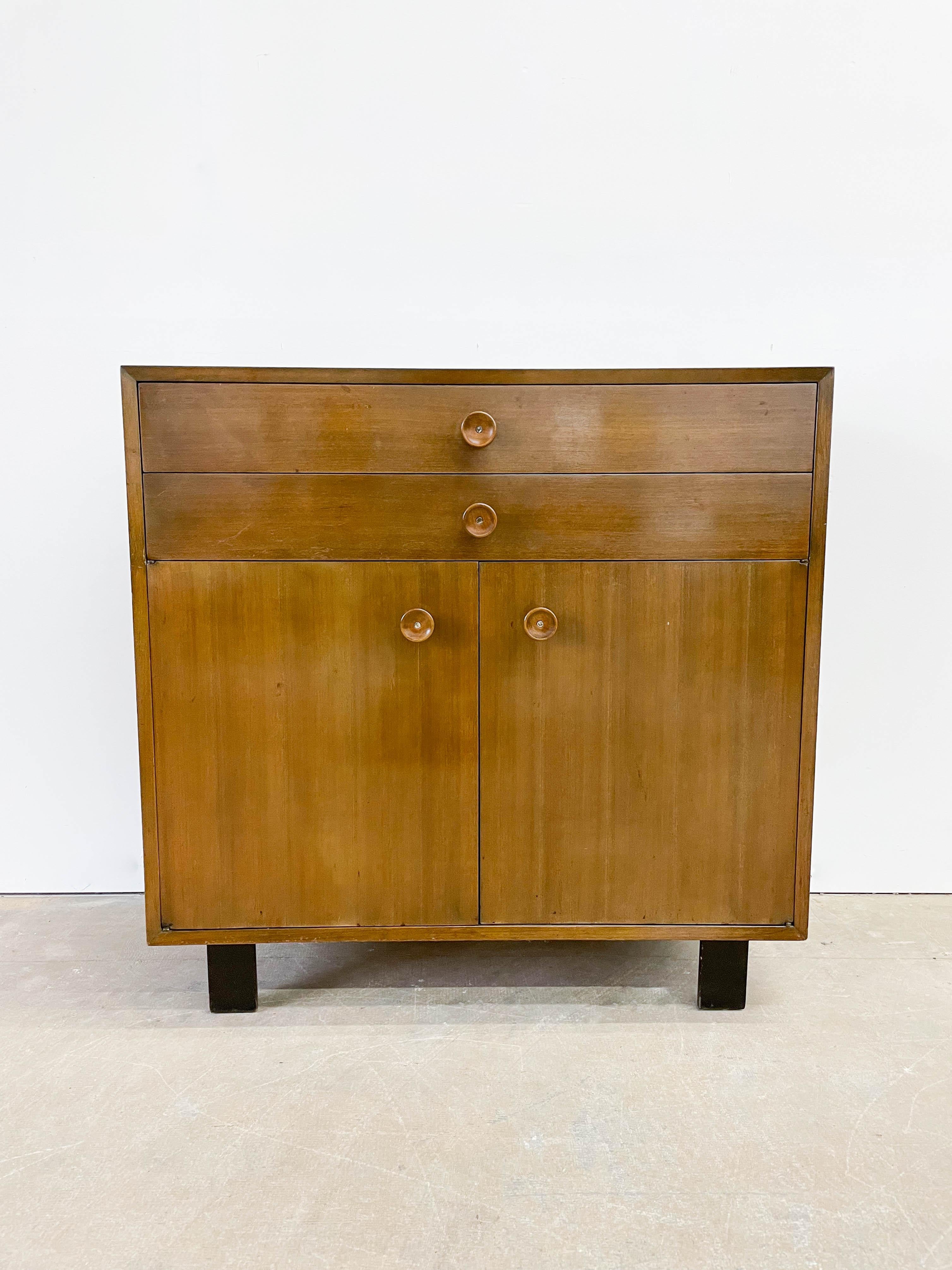 This is a very rare 1940s petite buffet cabinet designed by George Nelson for his first modern collection for Herman Miller in 1948. The buffet cabinet features cupcake pulls and a large storage at the bottom of the cabinet. Two sliding drawers at