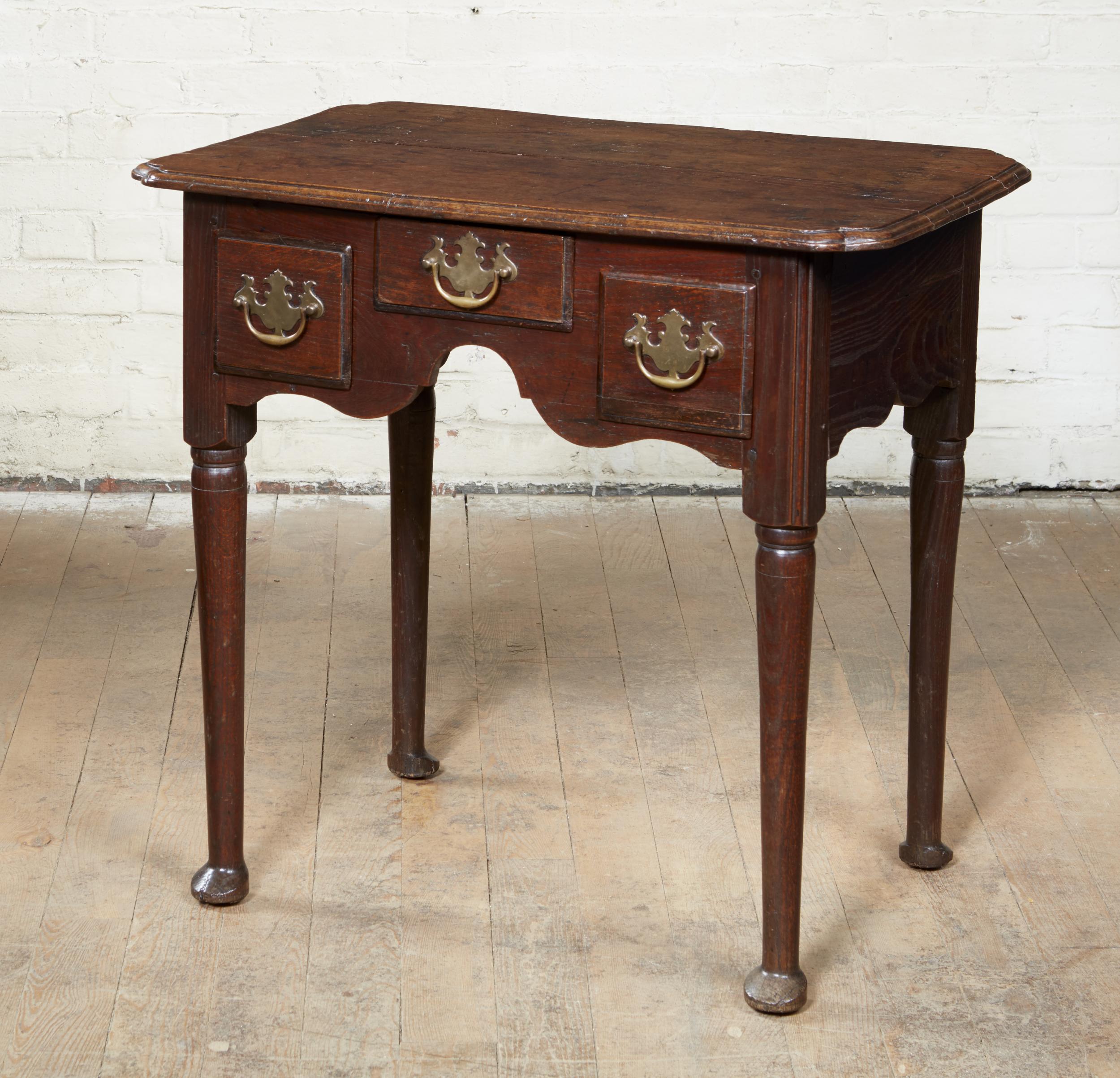 Fine George I period oak lowboy having exaggerated re-entrant (baby's bum) corners, over two deep and one shallow drawer each with brass batwing pulls, over scalloped apron and standing on turned legs ending in pad feet, unusually facing back to