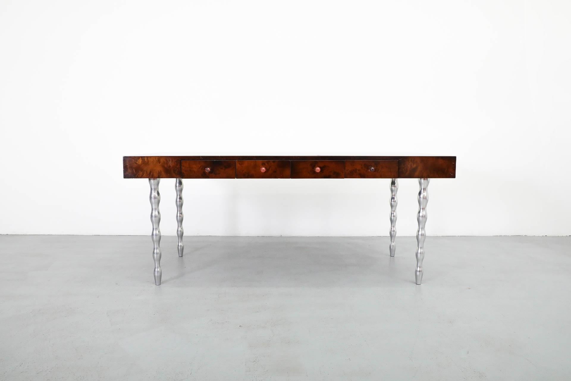 Uno de los primeros escritorios de Gerard Van Den Berg para Montis. El diseño es casi una mezcla de Saporiti y Sottsass, y la mesa está fabricada por expertos en hermosa madera burilada con patas torneadas de aluminio fundido. Van den Berg es