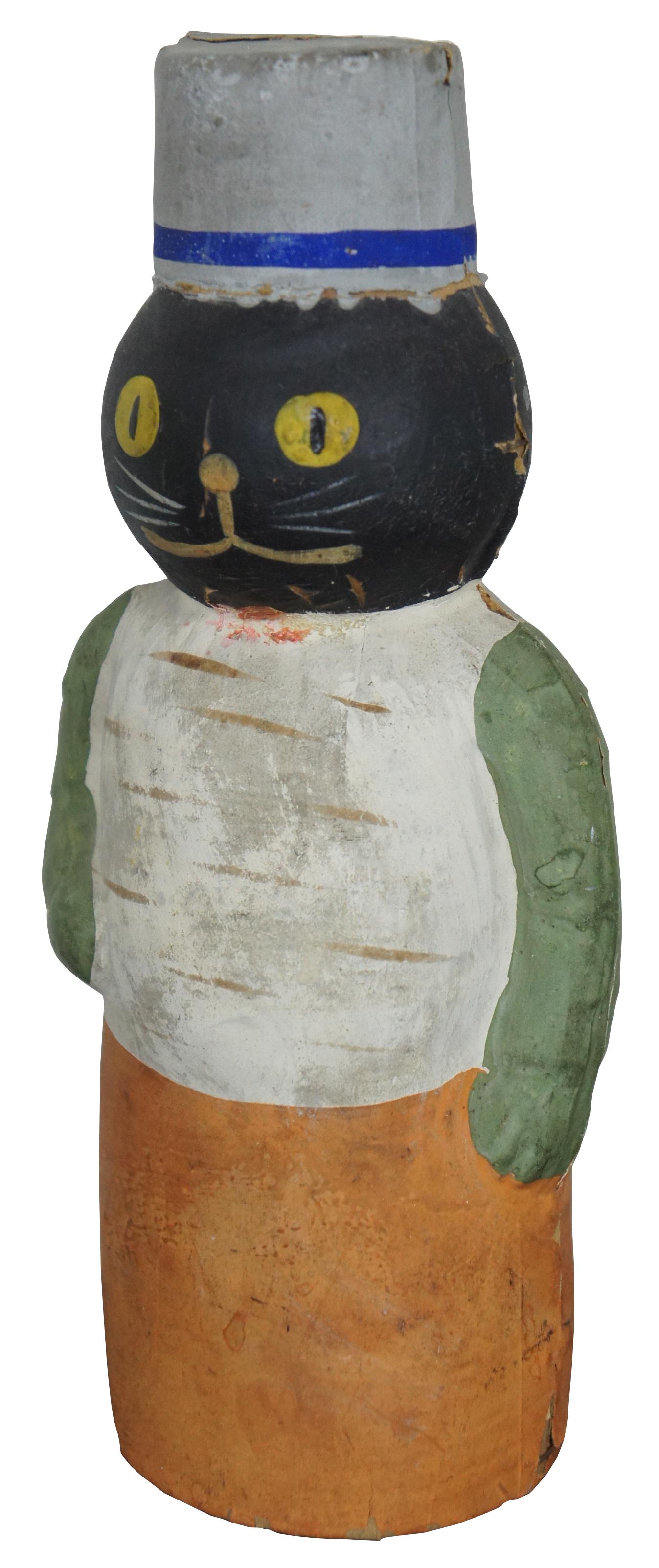 Antique German papier mâché anthropomorphic candy container, shaped like a black cat with yellow eyes dressed in orange, green and white with a gray pill box hat, displayed in a wood base bell jar.

Measures: Bell jar 6.25” x 10.75” / cat 3.5” x