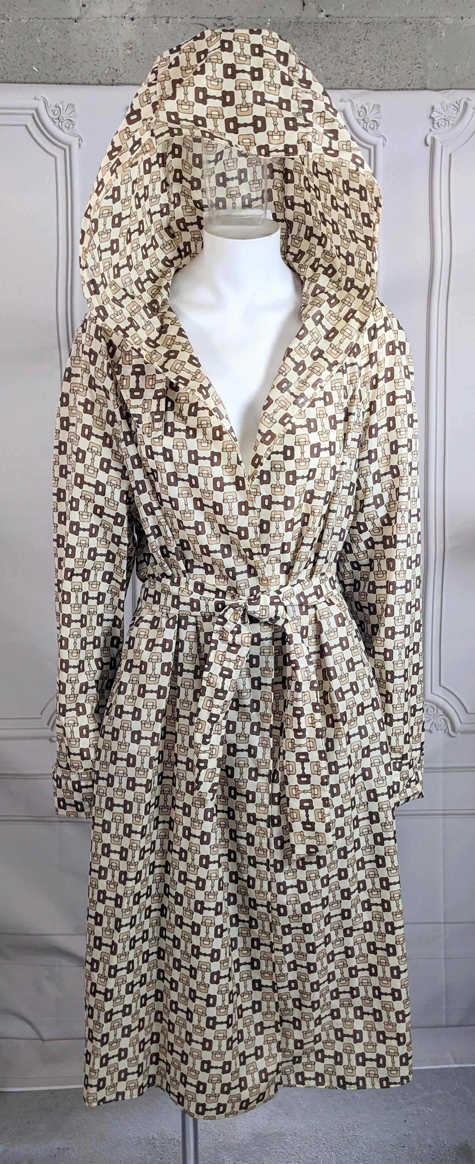Frühe Gucci Signatur Pferdegebiss Druck Nylon Regenmantel auf hellem Elfenbein Grund gedruckt in tan und braun Pferdegebiss Motive. Kapuze mit Gürtel und Messing-Emaille-Logo-Knöpfen an der Windschutzleiste. Das MATERIAL des Nylonschirms ist leicht
